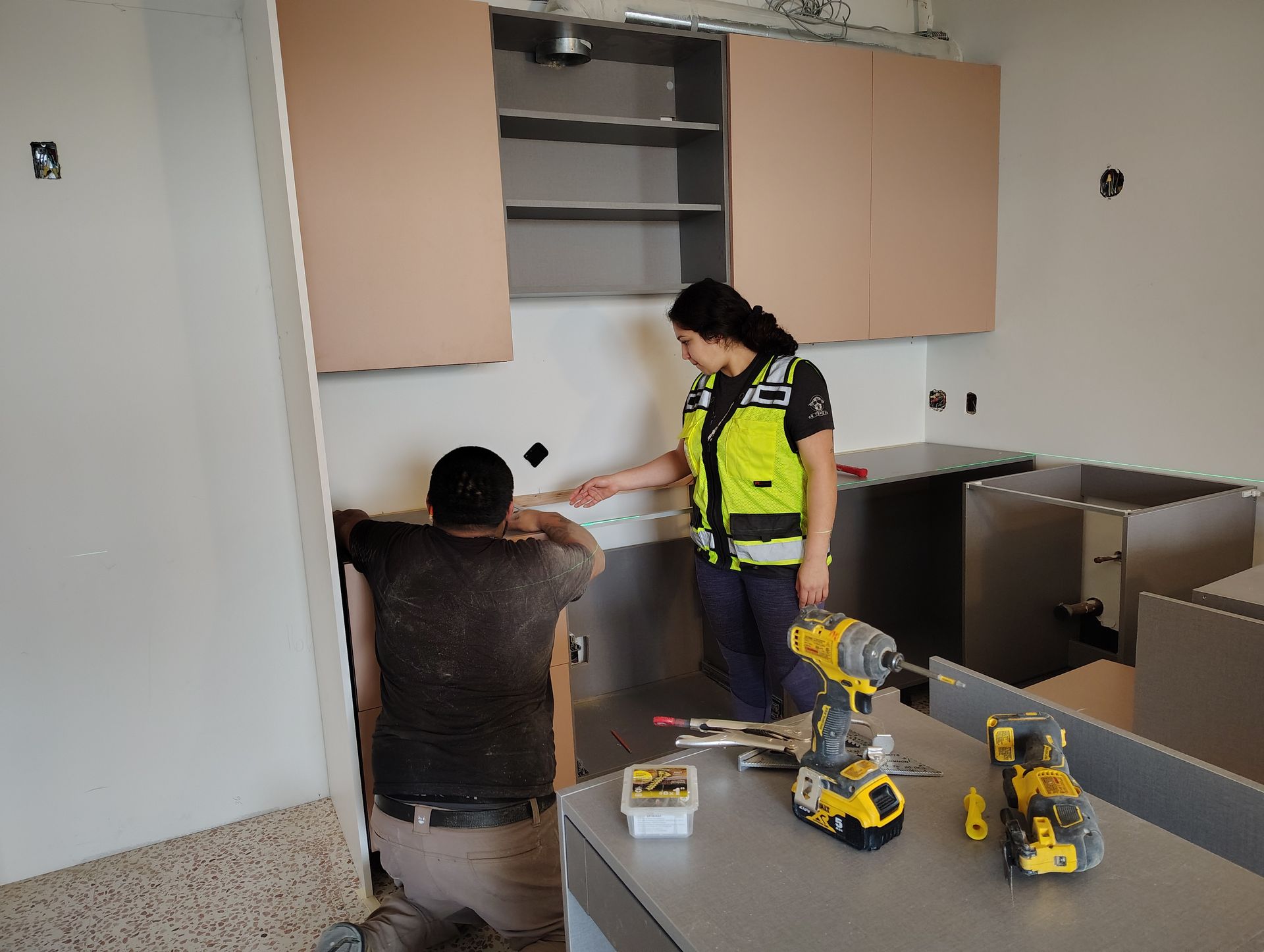 A man and a woman are working on a kitchen.