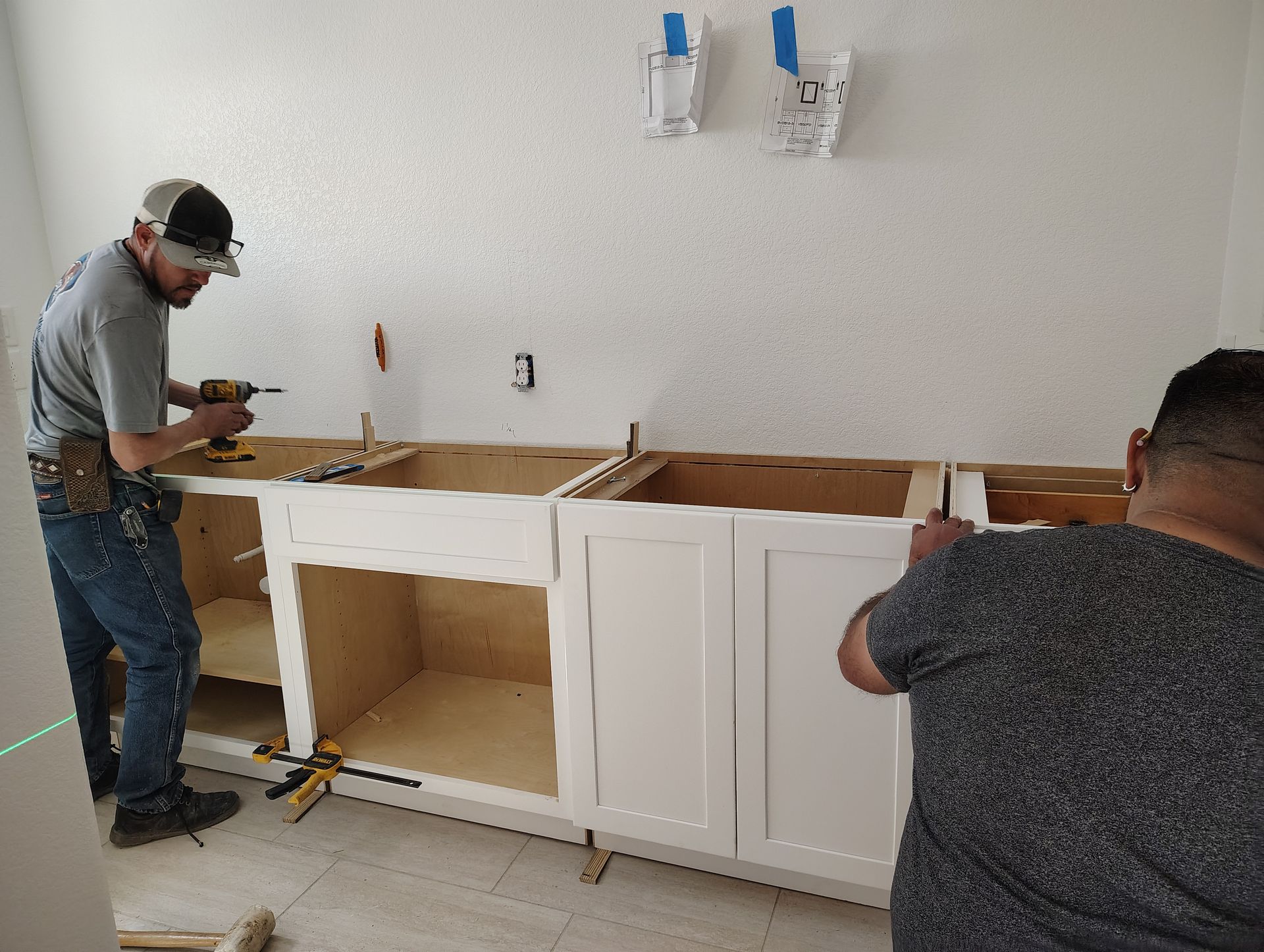 Two men are working on a kitchen counter.