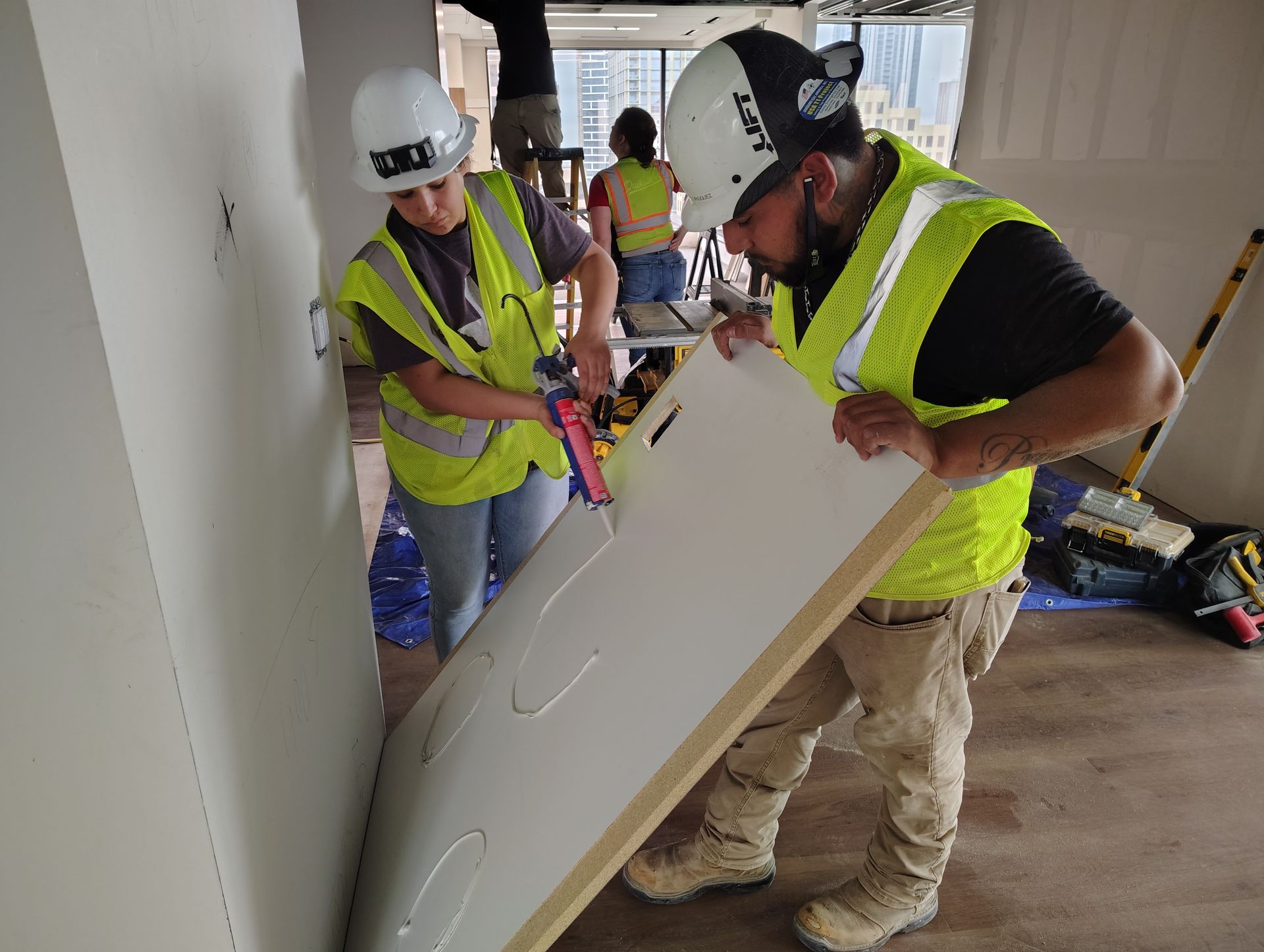 A man and a woman are working on a large piece of wood.