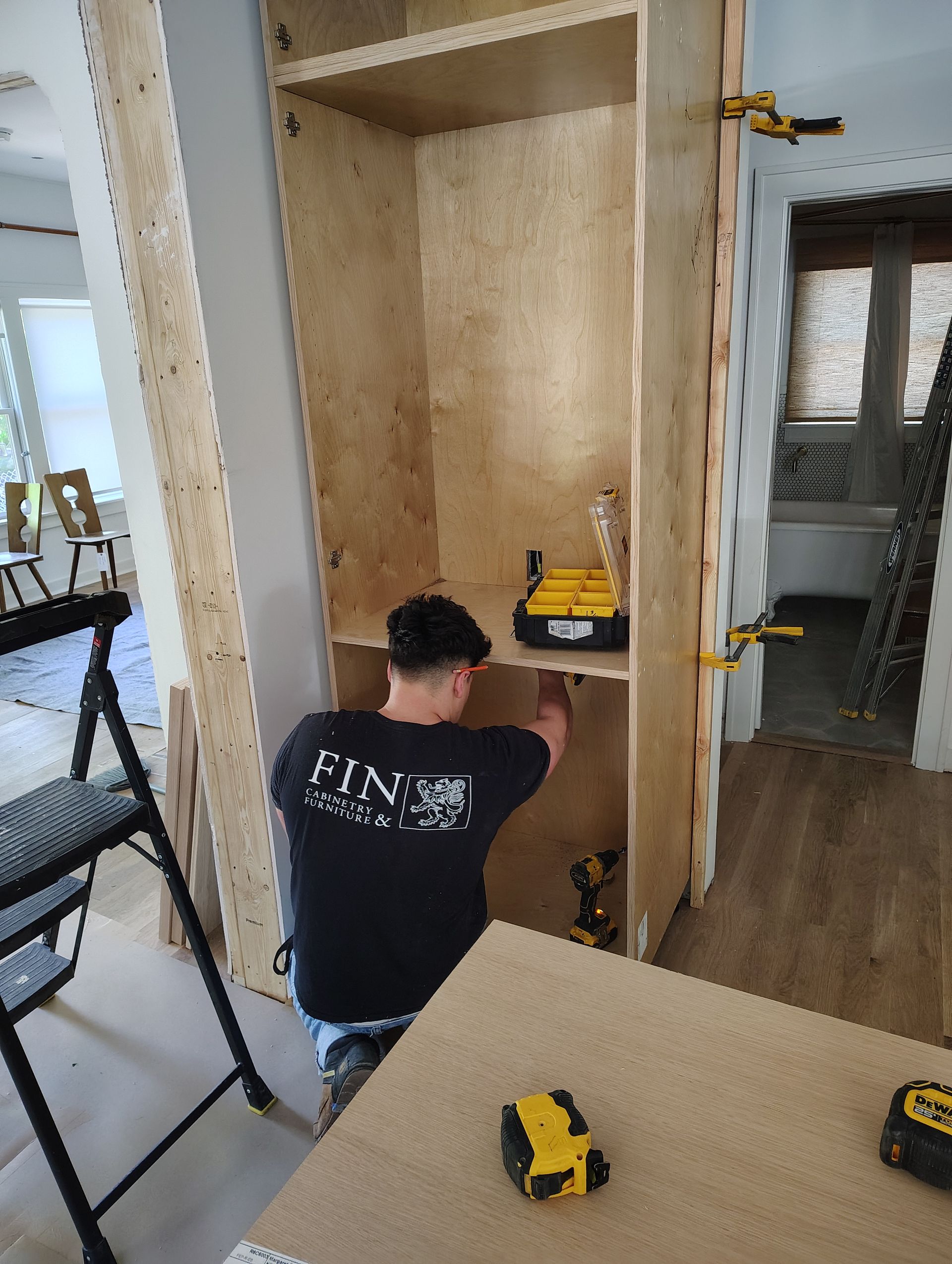 A man is working on a wooden cabinet in a room.