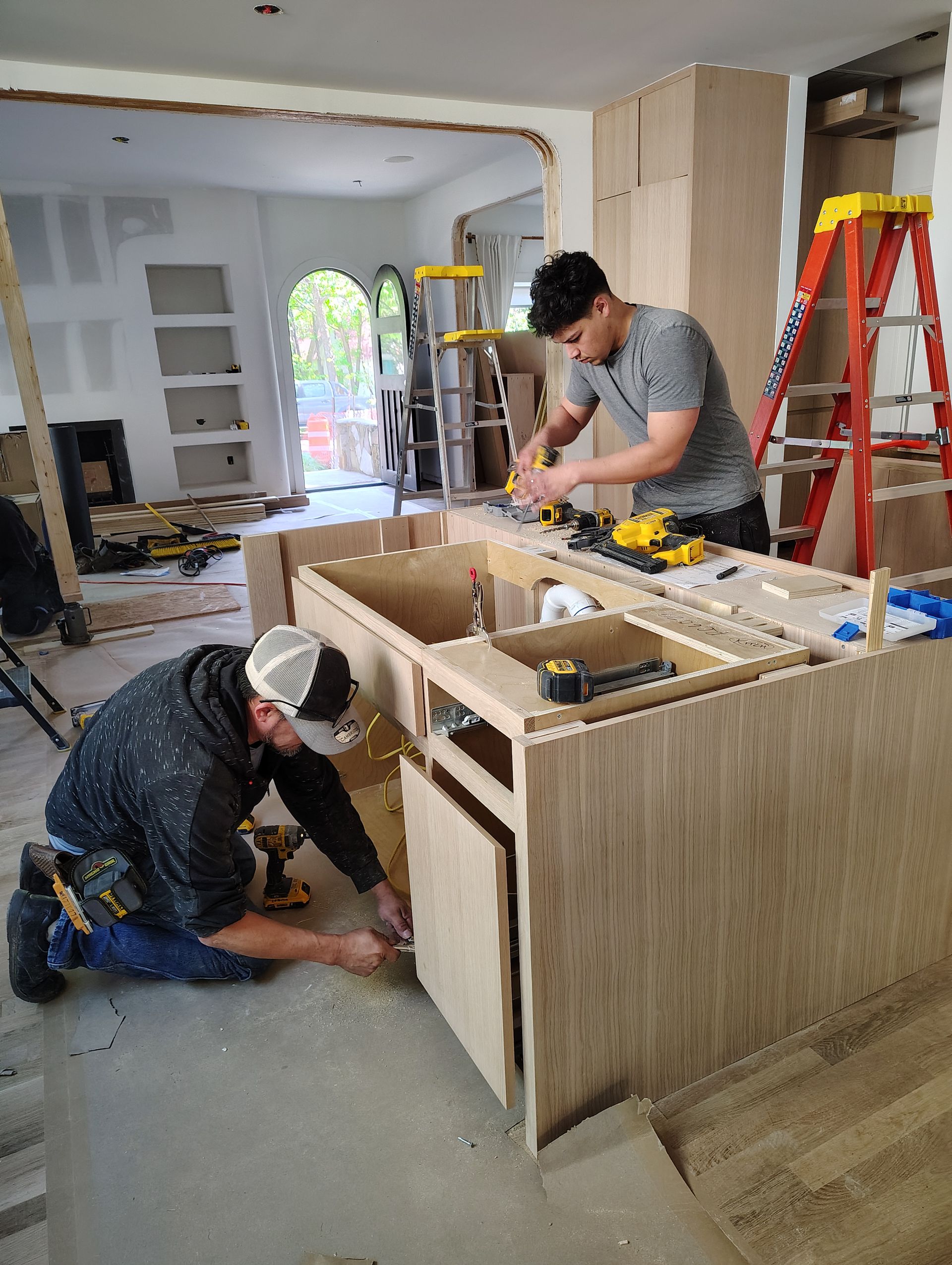 Two men are working on a kitchen island.
