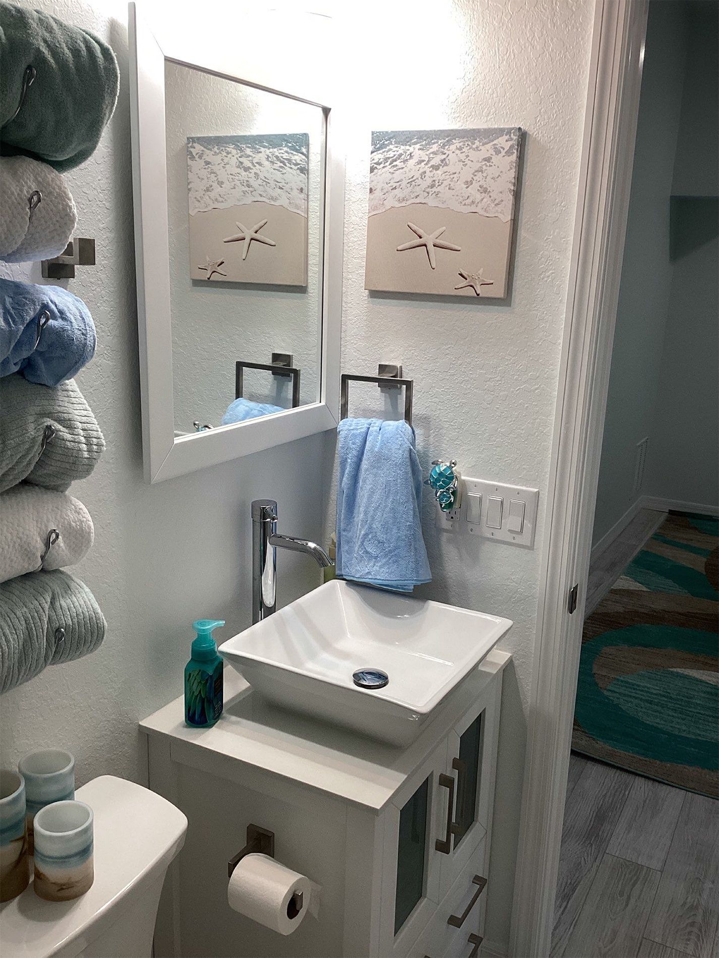 A bathroom with a sink , toilet , mirror and towels.