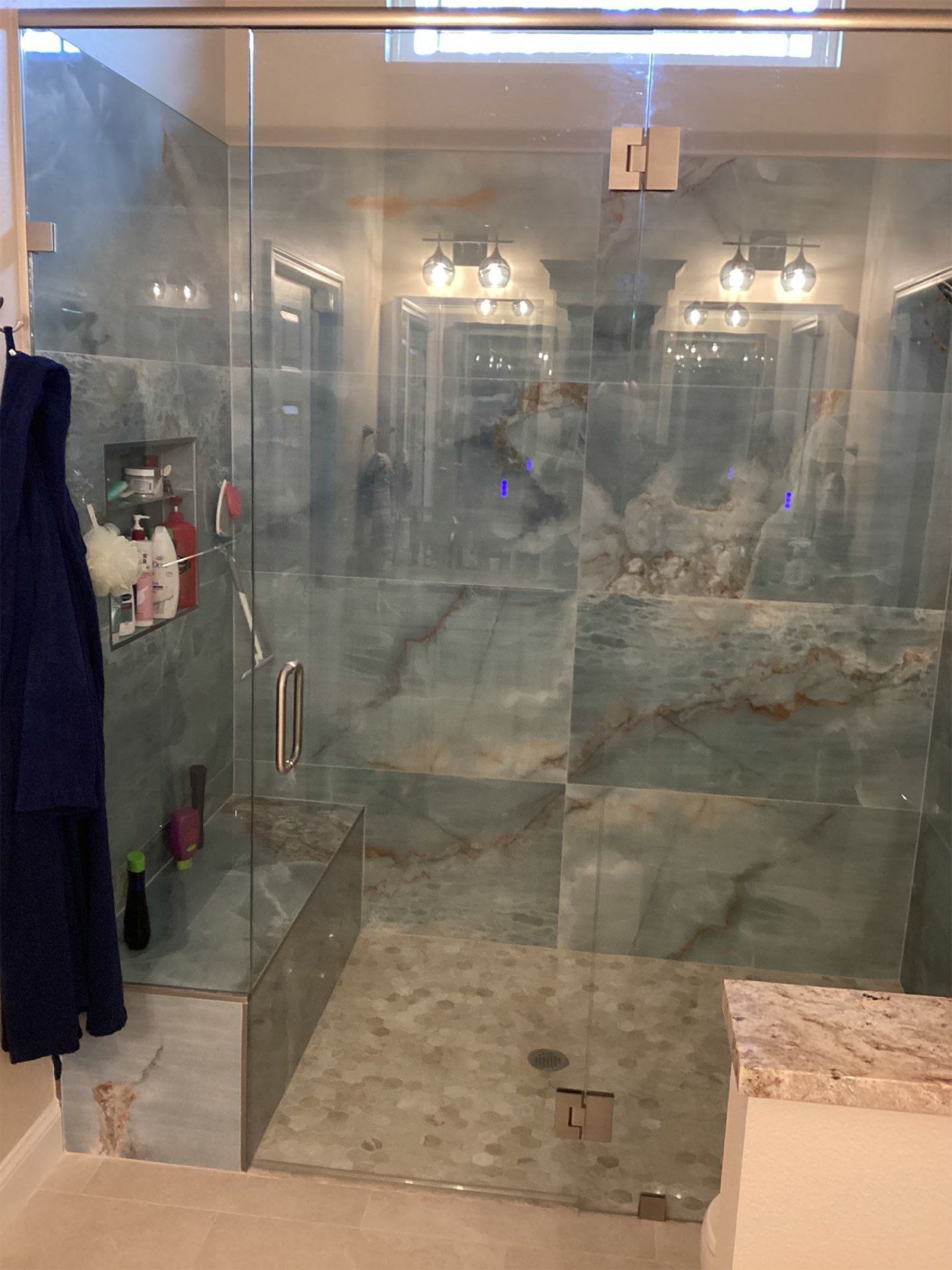 A bathroom with a walk in shower with a glass door.