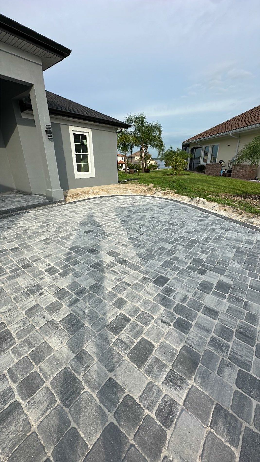 A brick driveway is being built in front of a house.