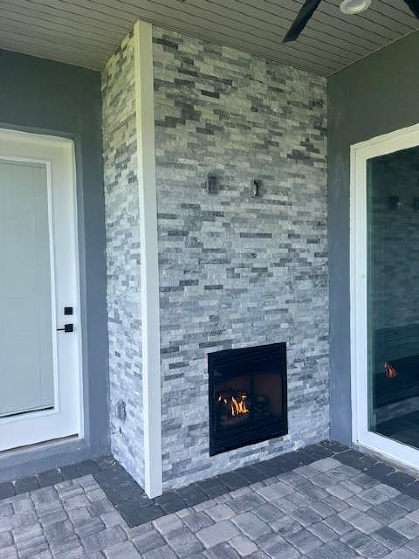 A fireplace is built into a stone wall on a patio.