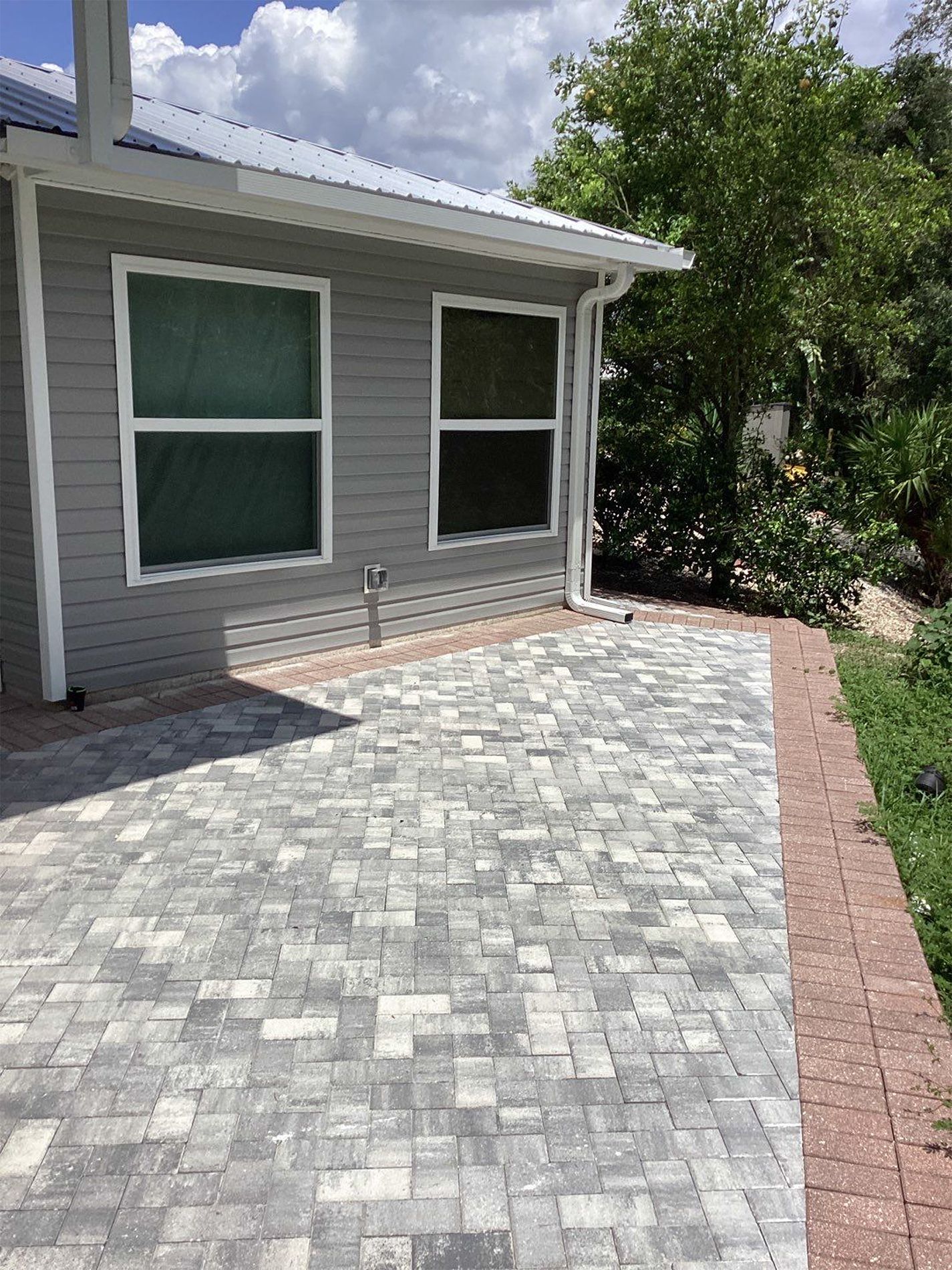 A house with a brick driveway and a brick walkway leading to it.