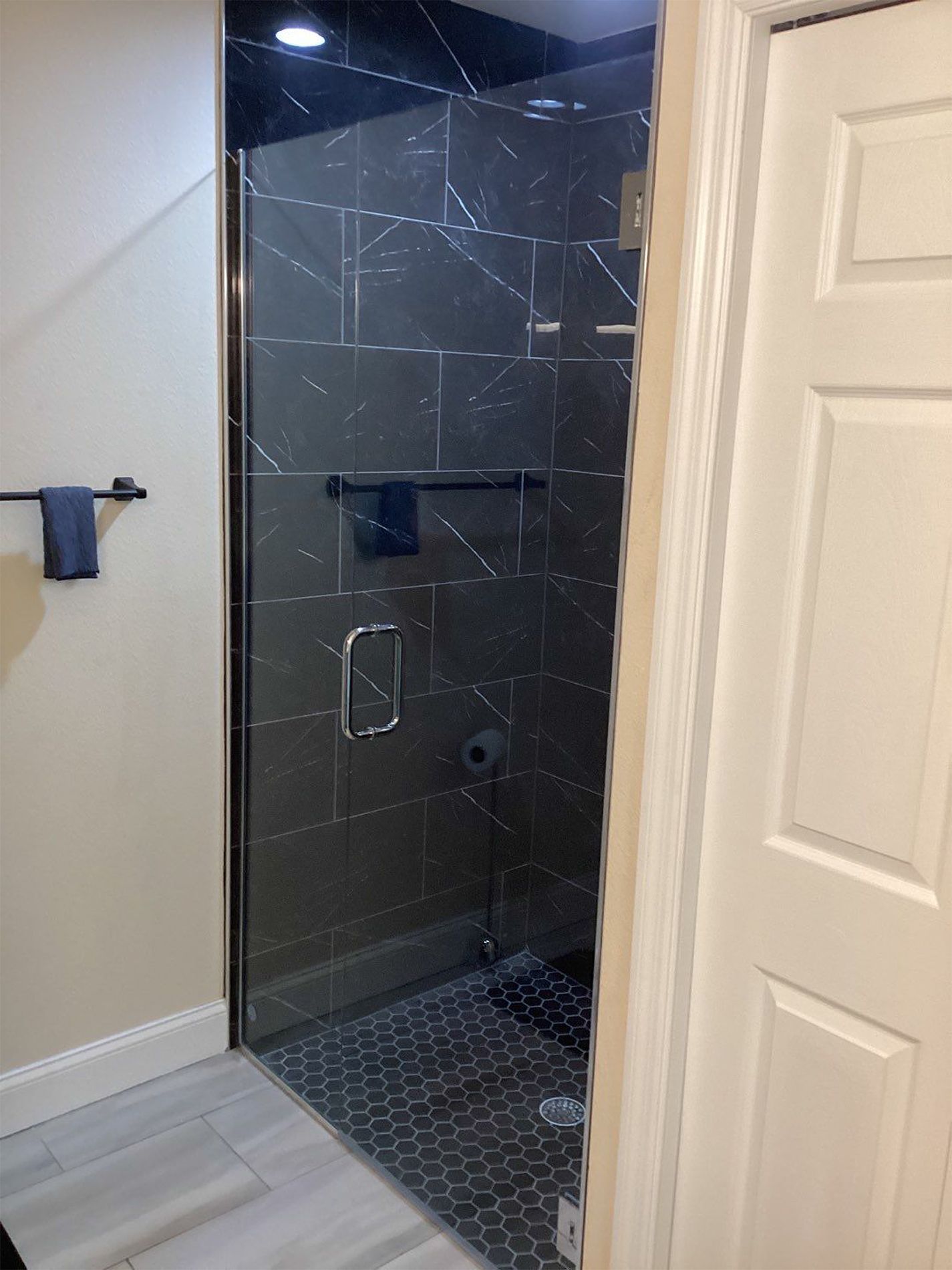 A bathroom with a walk in shower with a glass door.
