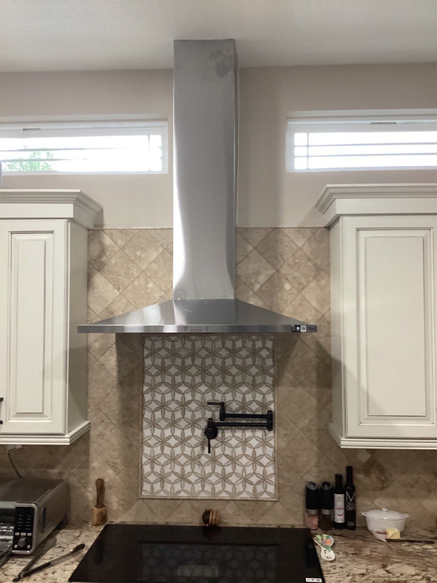 A kitchen with a stainless steel hood above the stove.