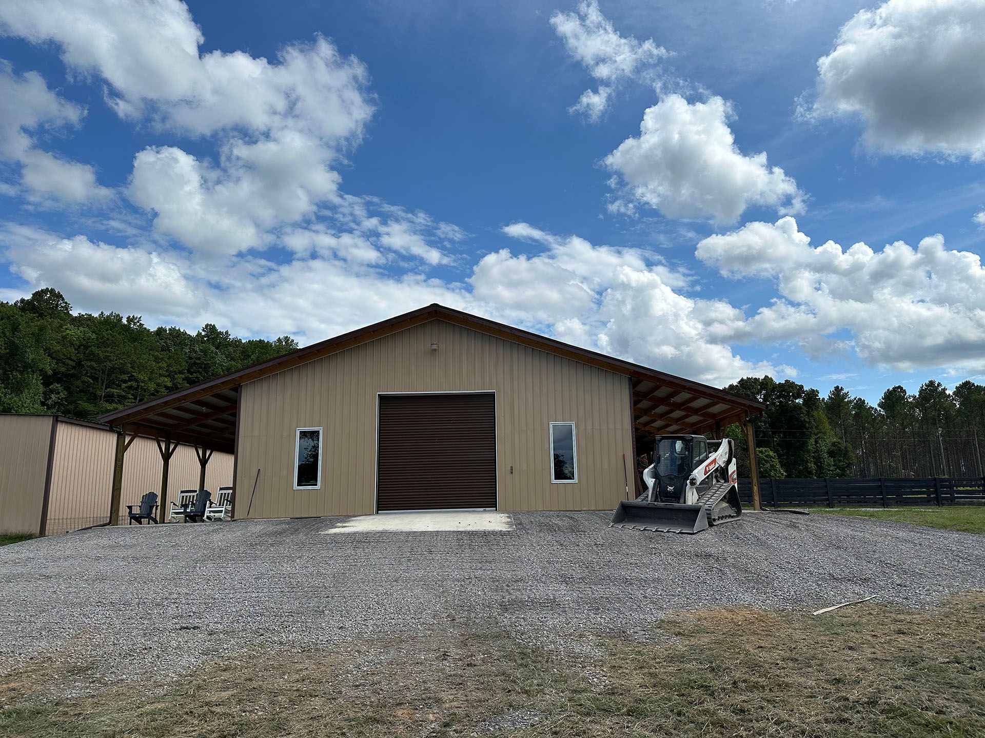 A large building with a garage door is sitting on top of a gravel lot.