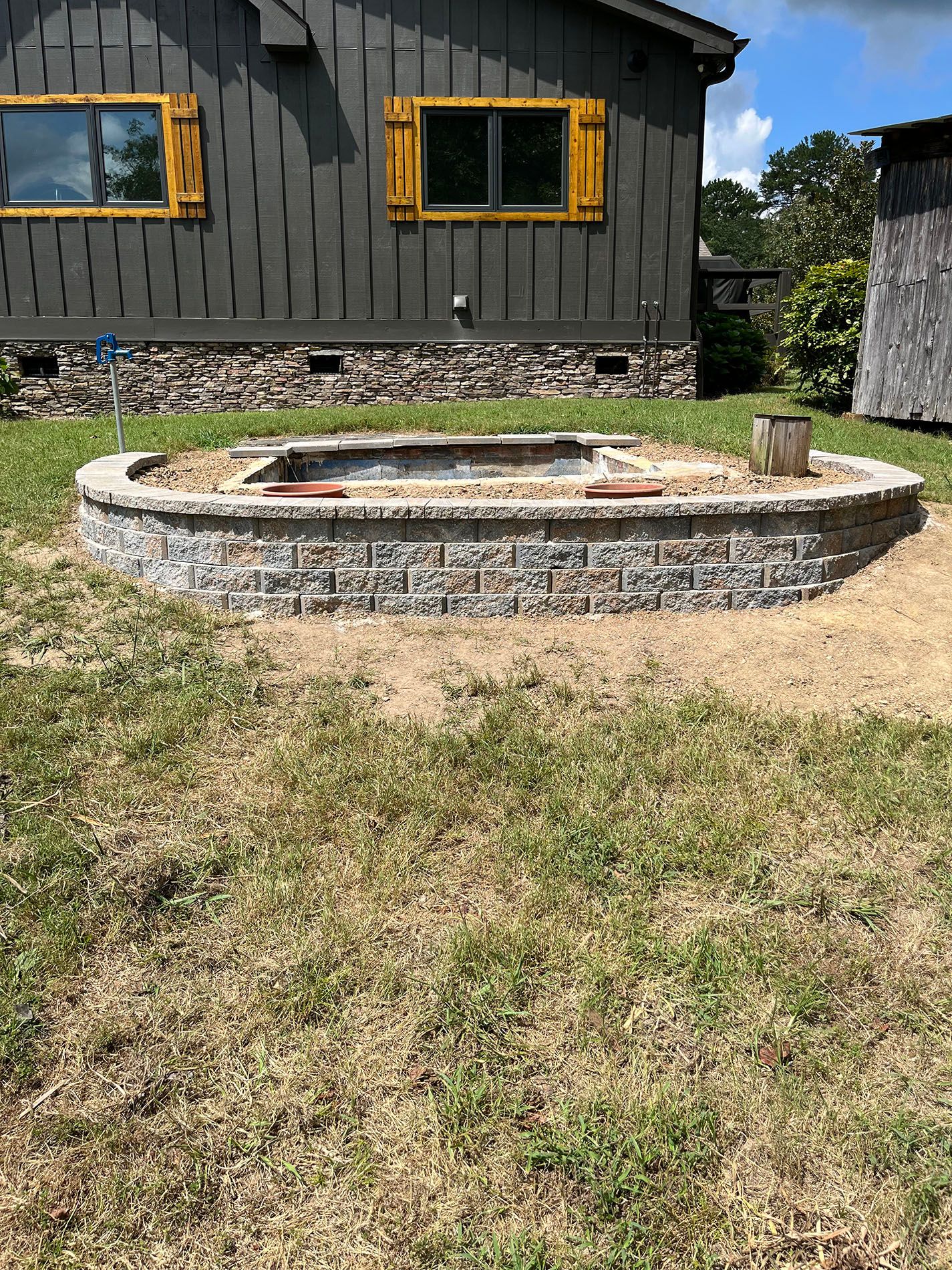 A fire pit is sitting in the grass in front of a house.