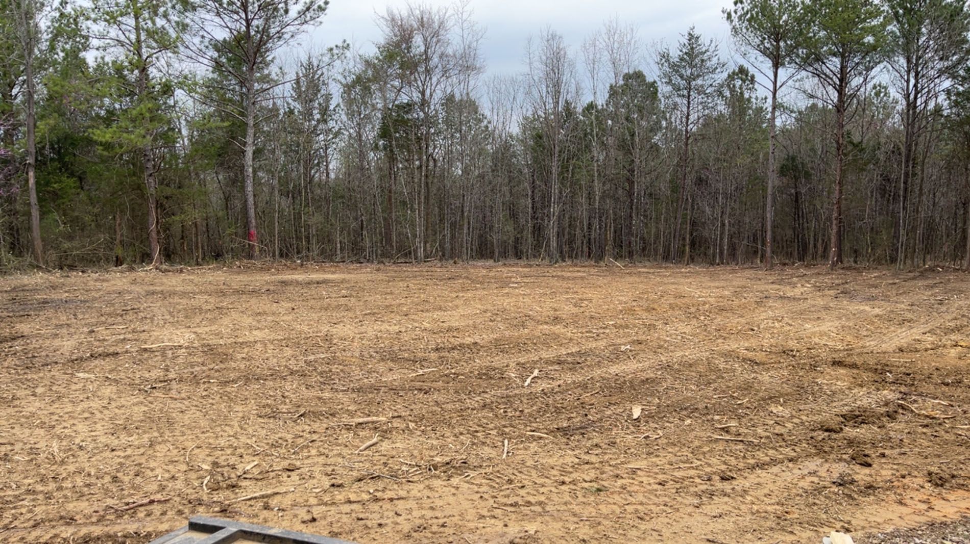 A large dirt field with trees in the background.