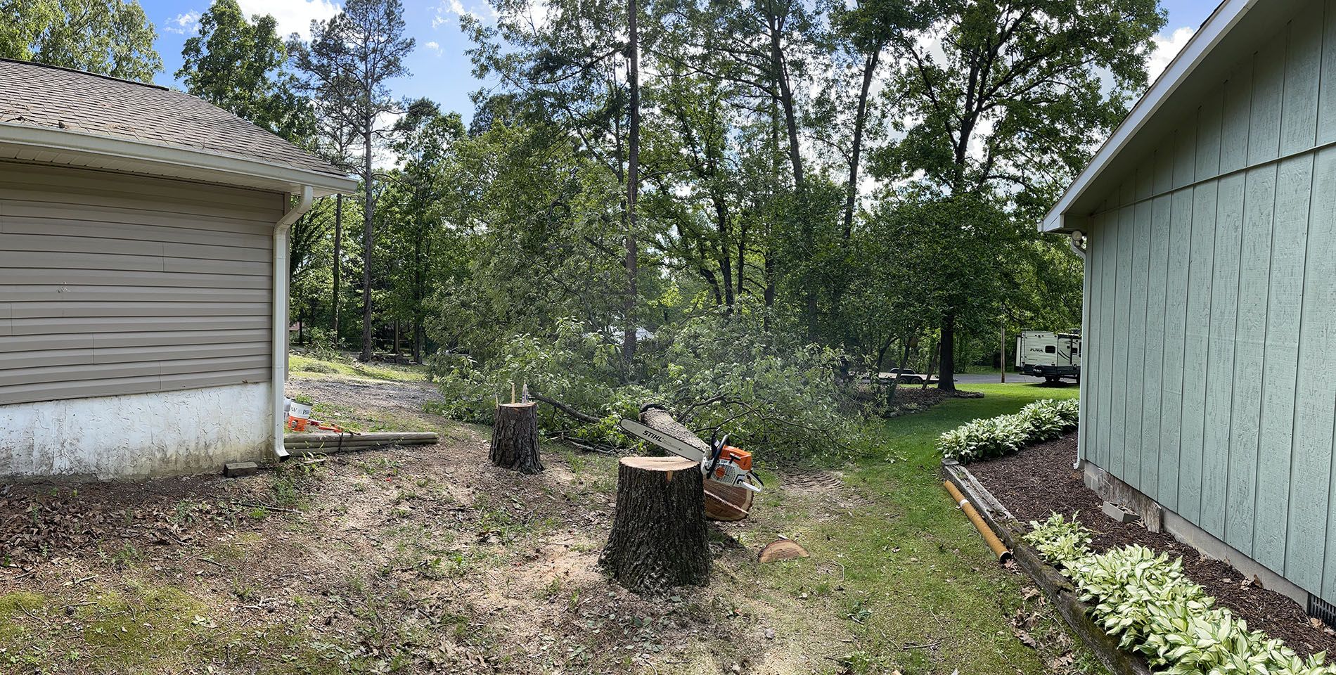 A tree stump is sitting in the middle of a yard next to a house.