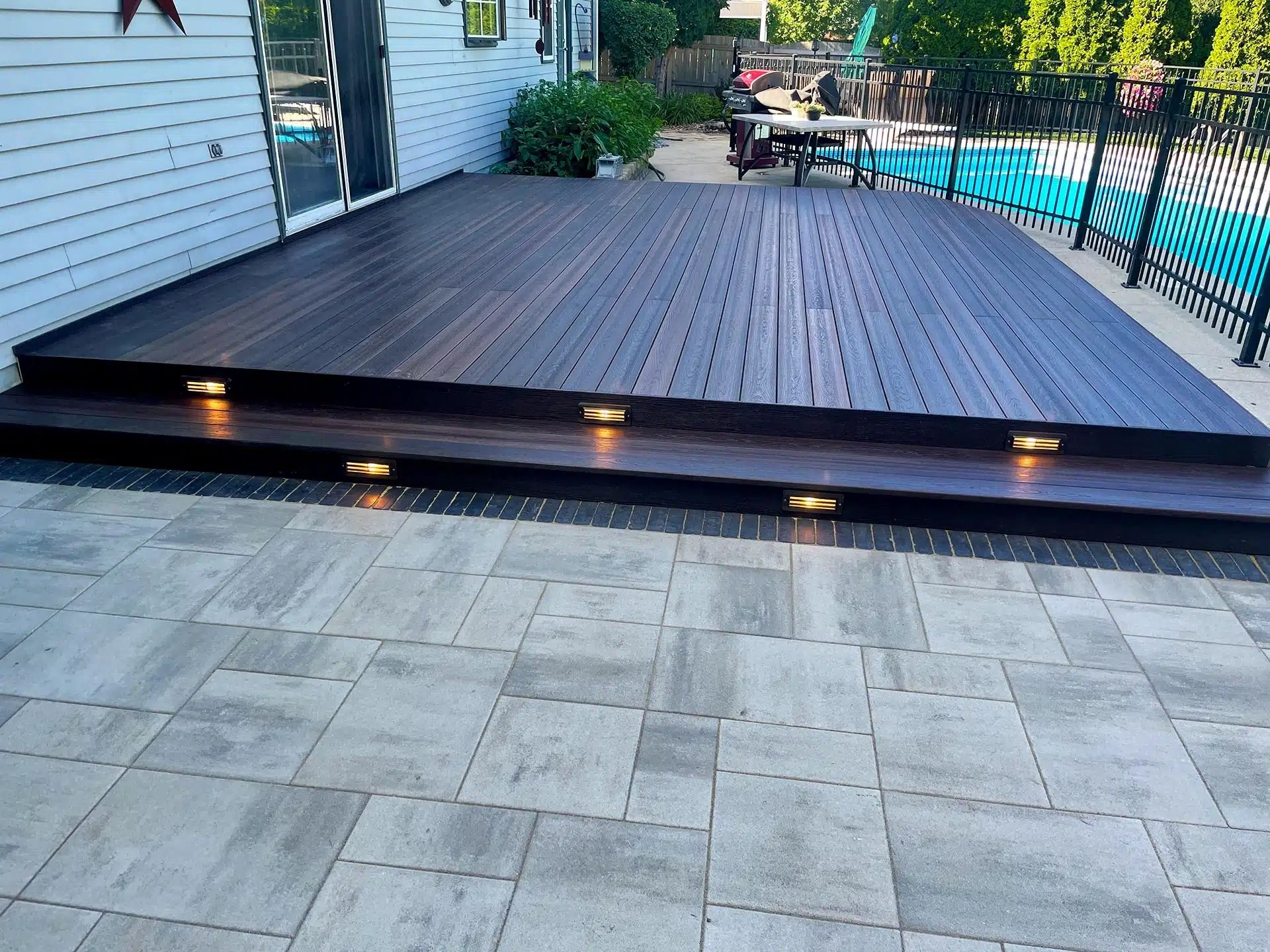 Wooden deck with steps, built-in lights, and a brick patio.