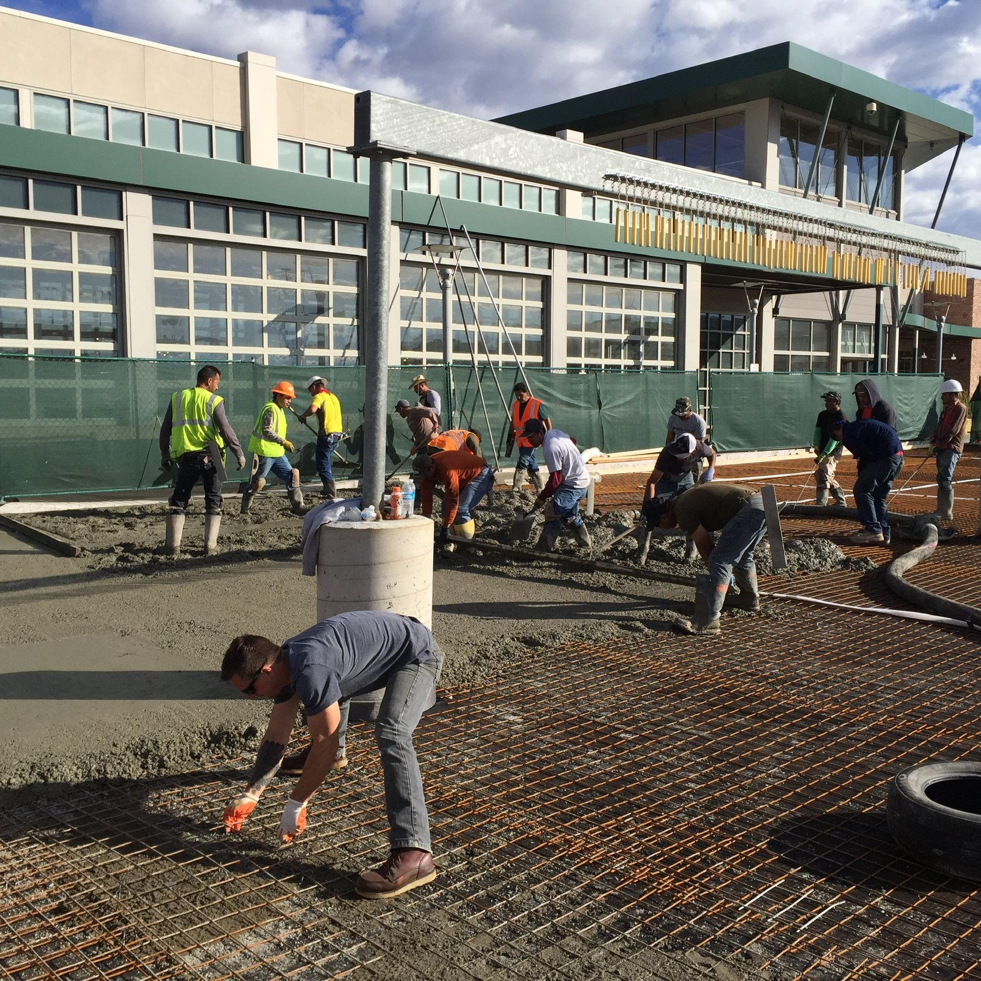 A group of construction workers are working on a sidewalk in front of a building.