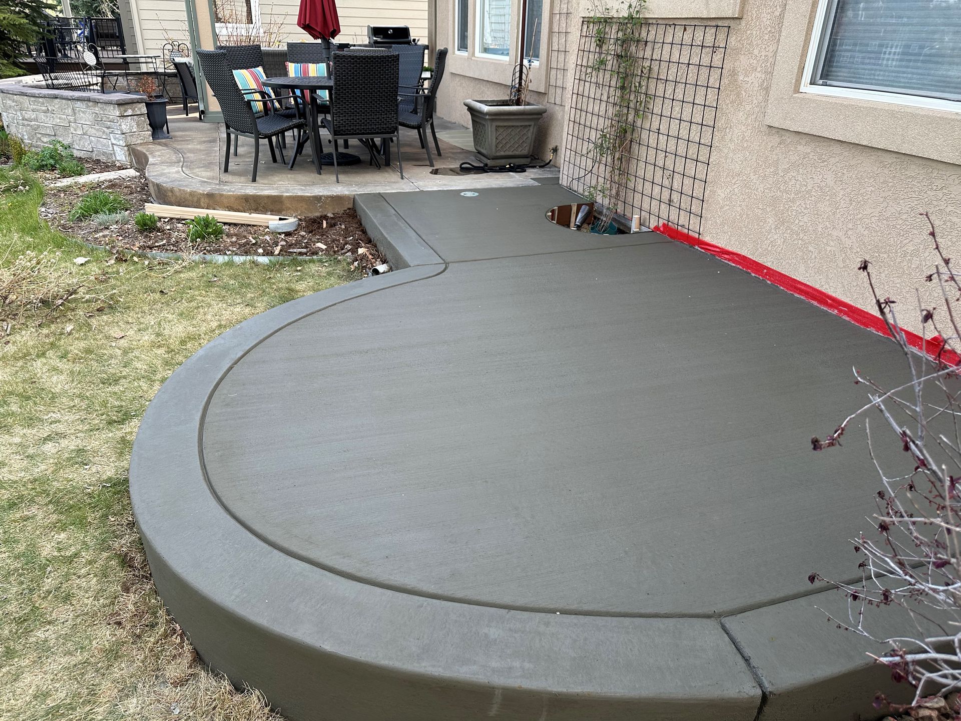 A concrete patio with a table and chairs is being built in front of a house.