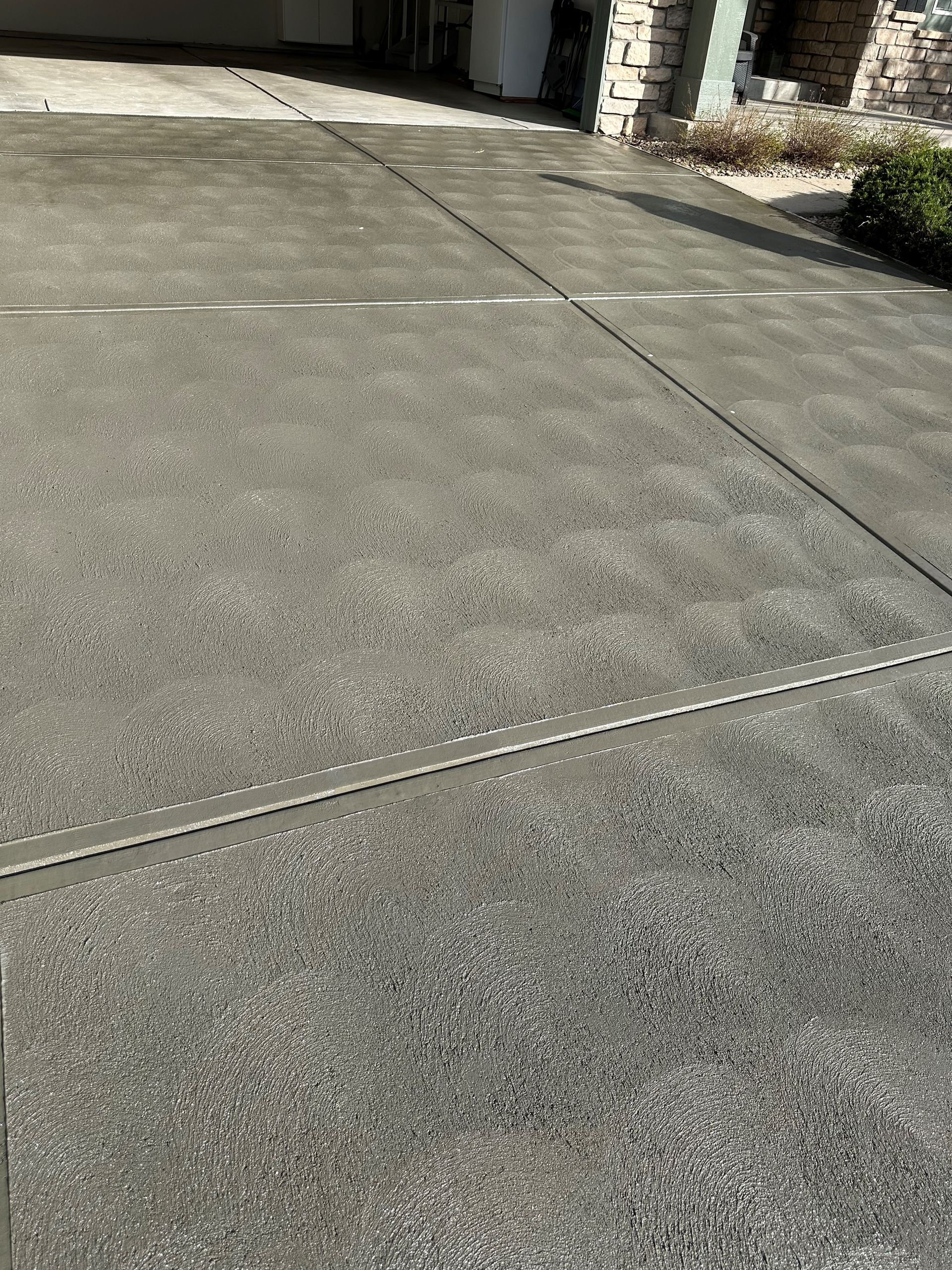 A close up of a concrete driveway in front of a house.
