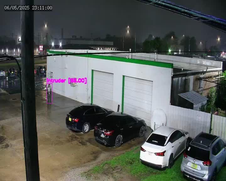 Nighttime parking lot beside a white garage, with four parked cars and a fence.