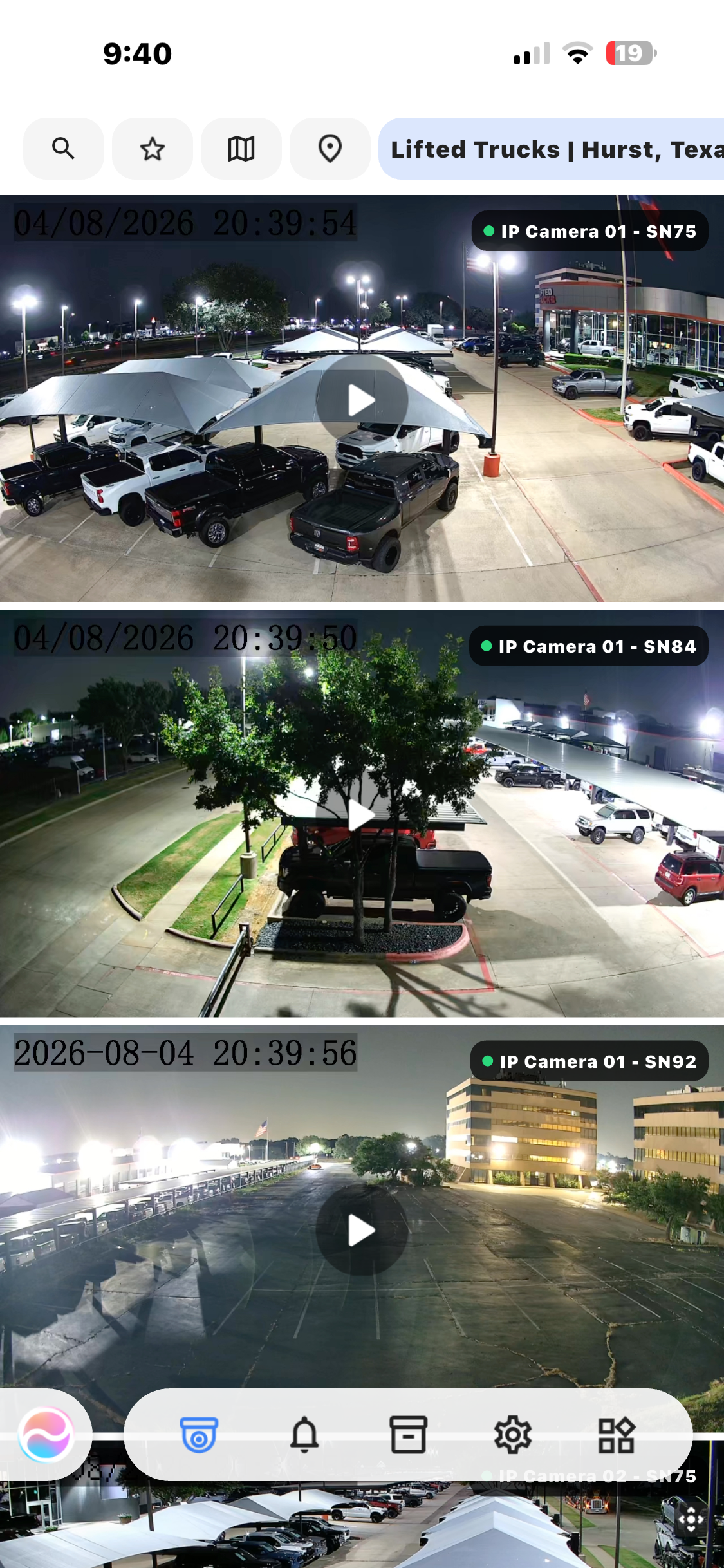 CCTV app screen showing three night-time parking lot camera views with parked cars and streetlights