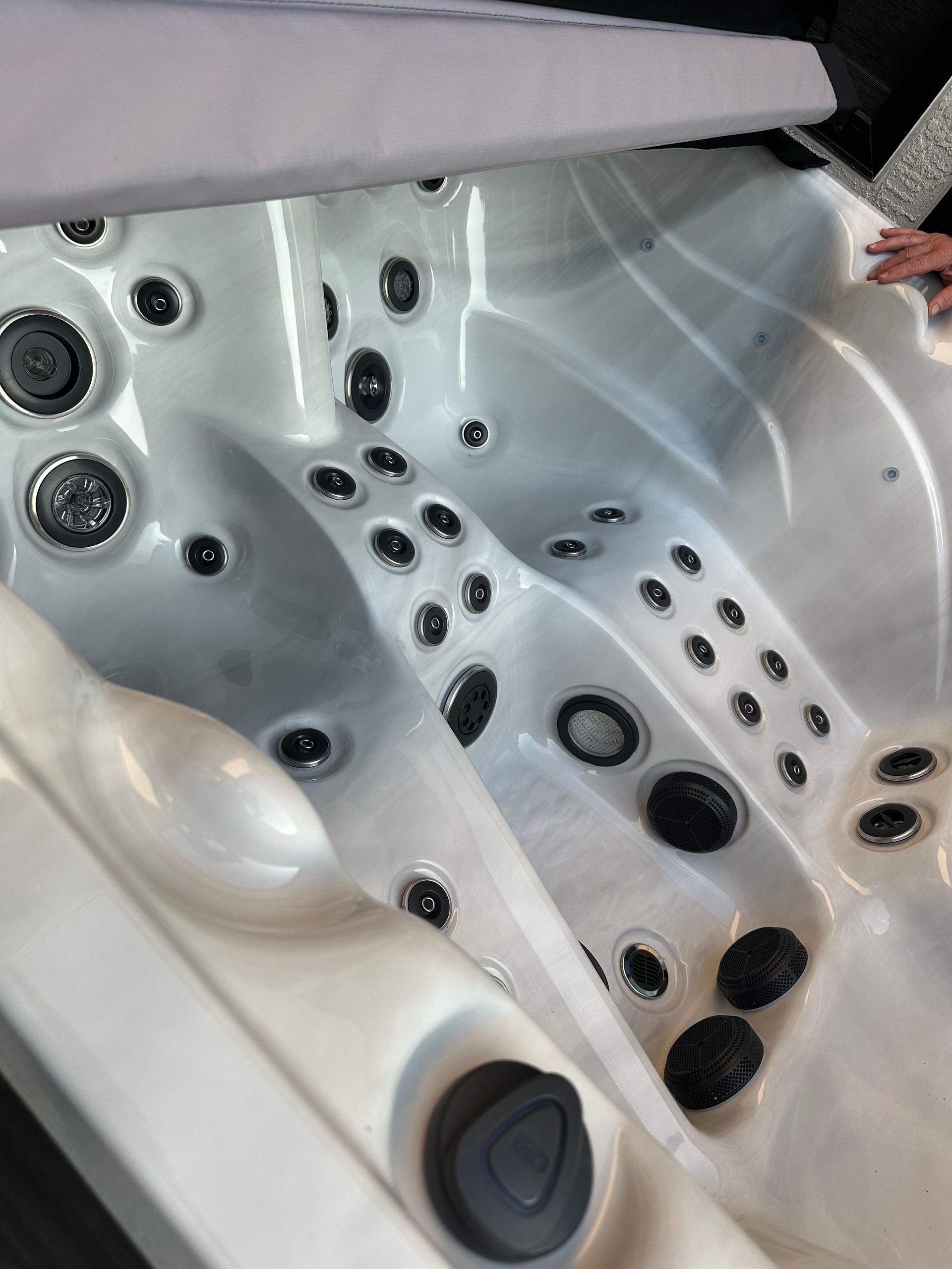 White hot tub interior with various jet nozzles and partially open cover.