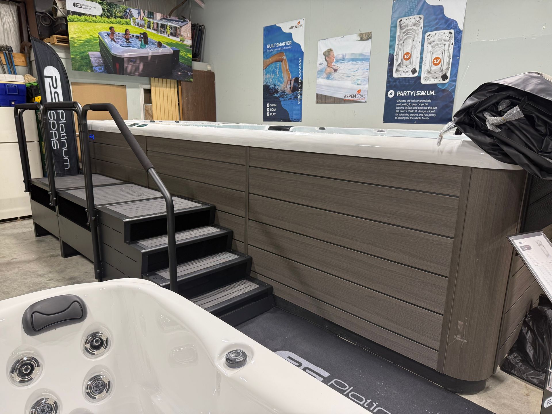 Swim spa with attached steps and handrails, displayed indoors.