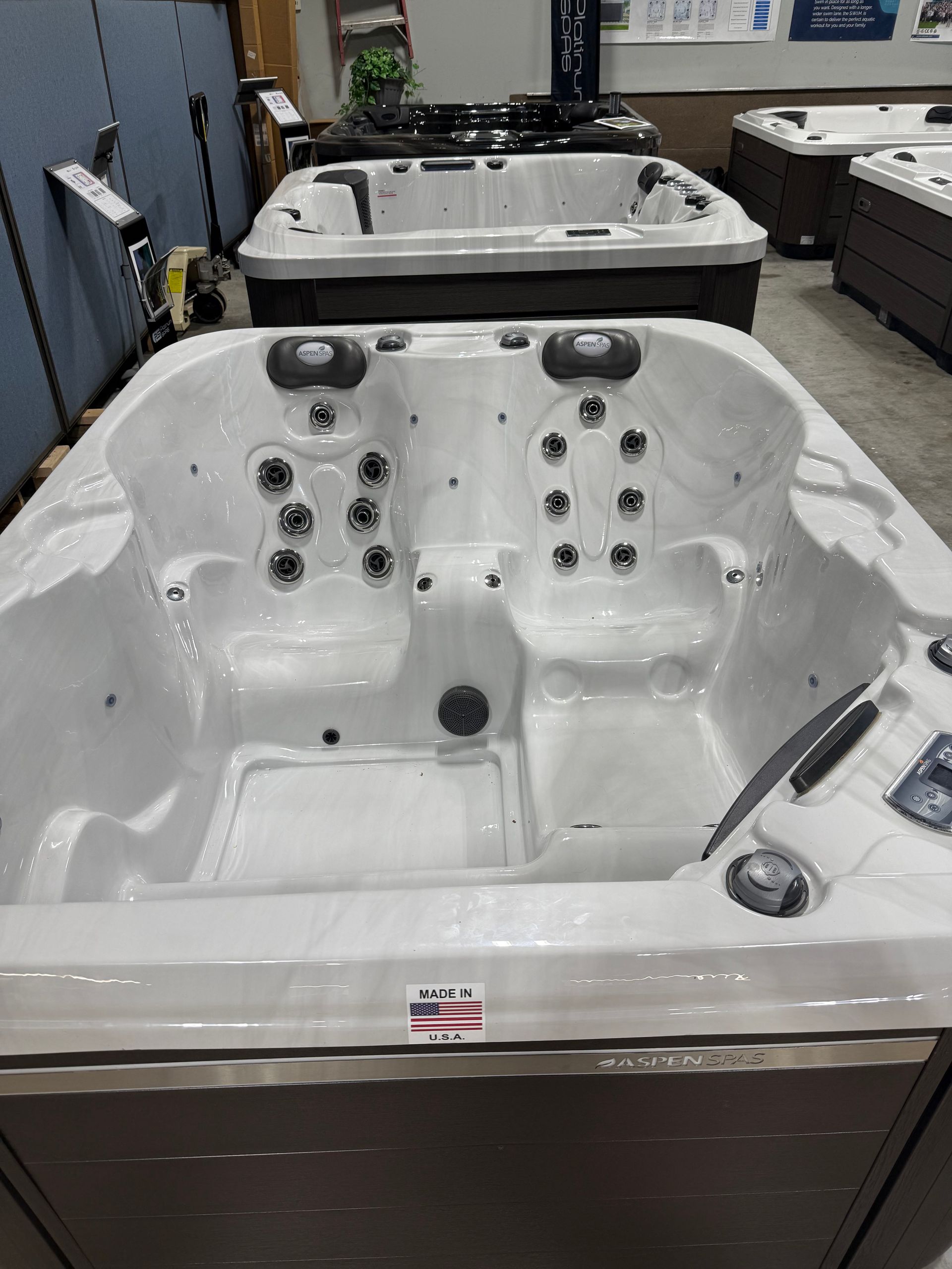 White hot tub with multiple jets on display in a store, with others in background.