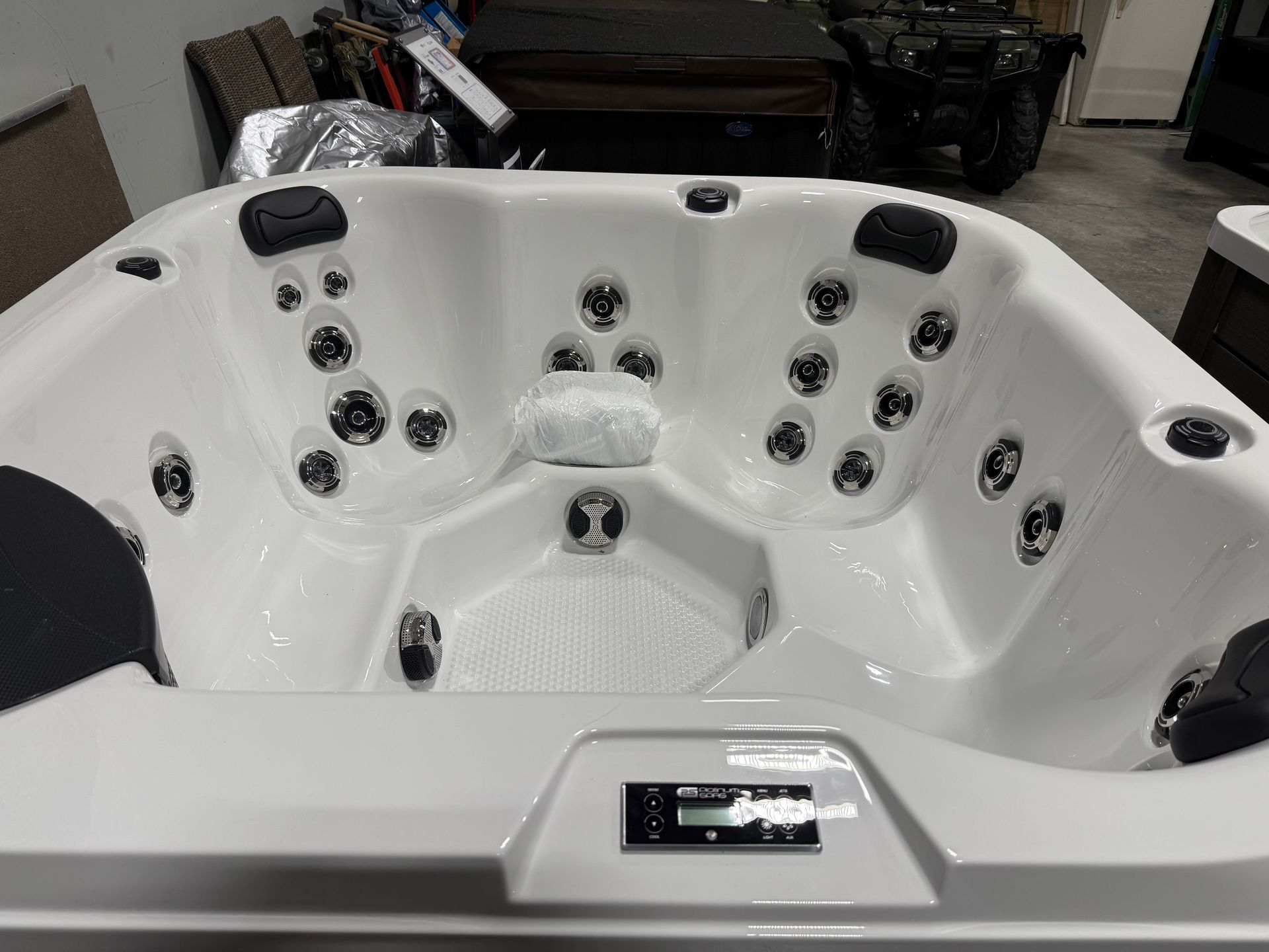 White hot tub with multiple jets, control panel, and seating for multiple people.