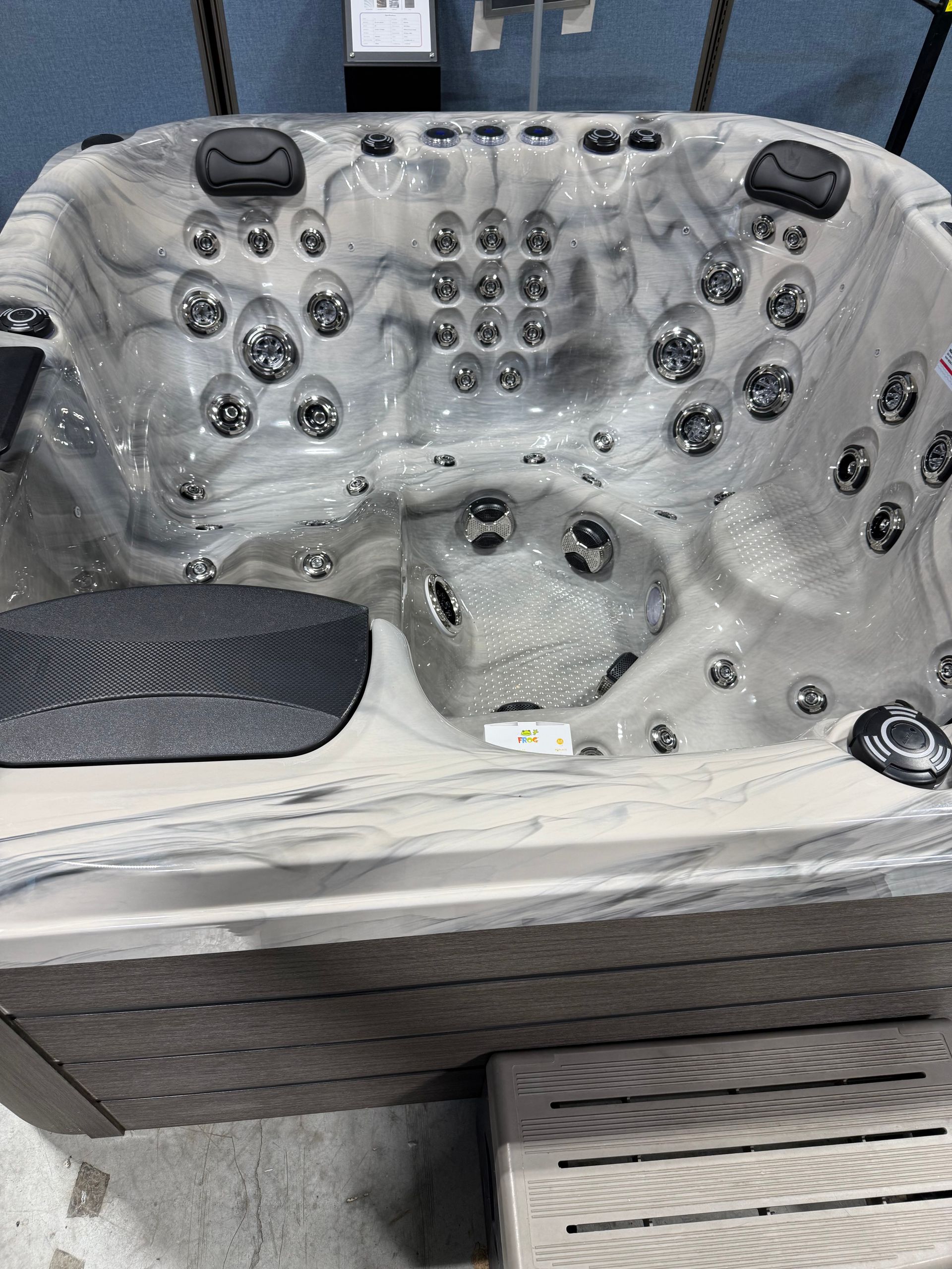 Gray marbled hot tub with numerous jets and dark gray headrests.