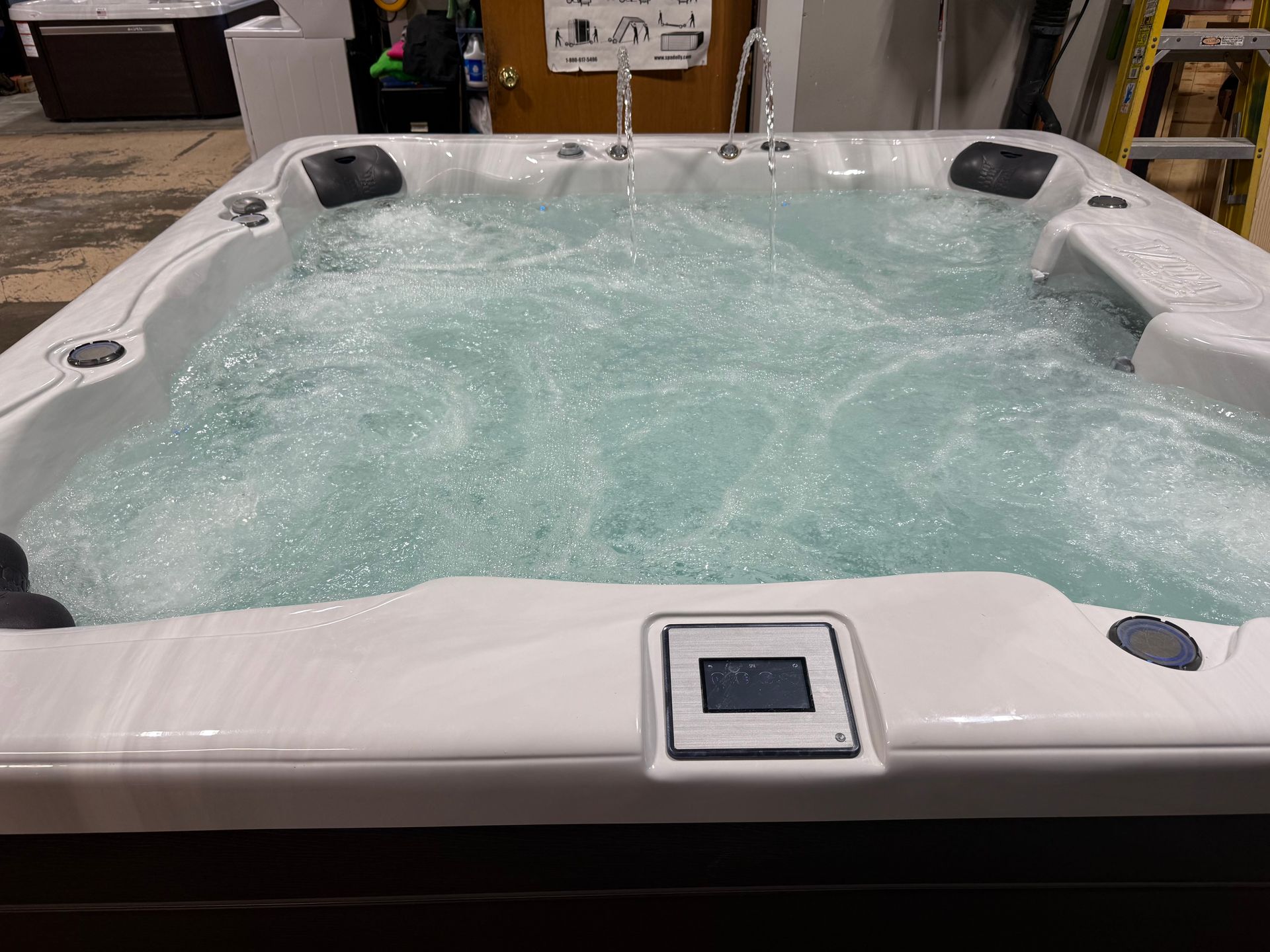 Bubbling hot tub with white trim, water, and control panel.