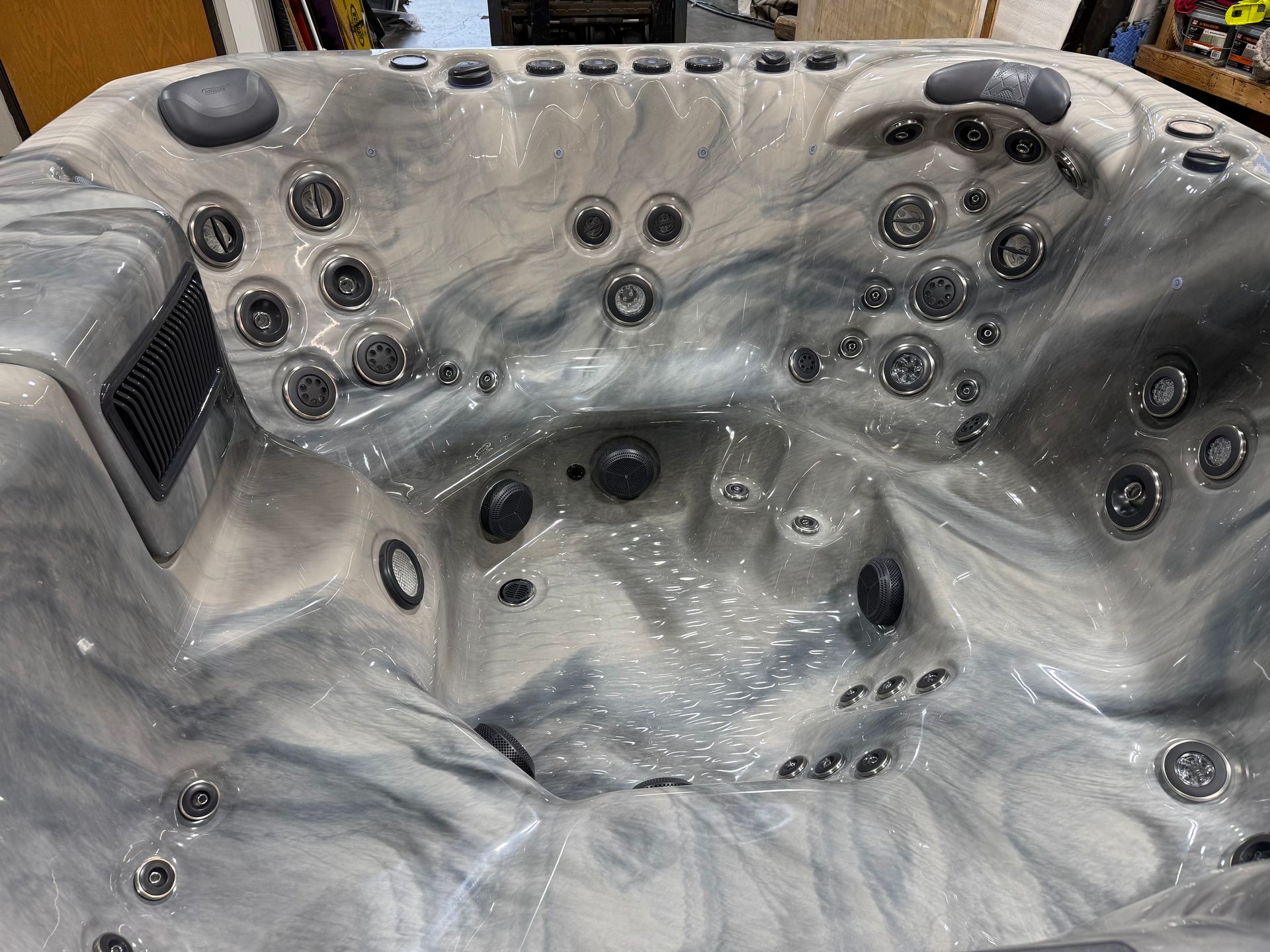 Inside view of a gray and white marble-patterned hot tub with many jet nozzles and controls.