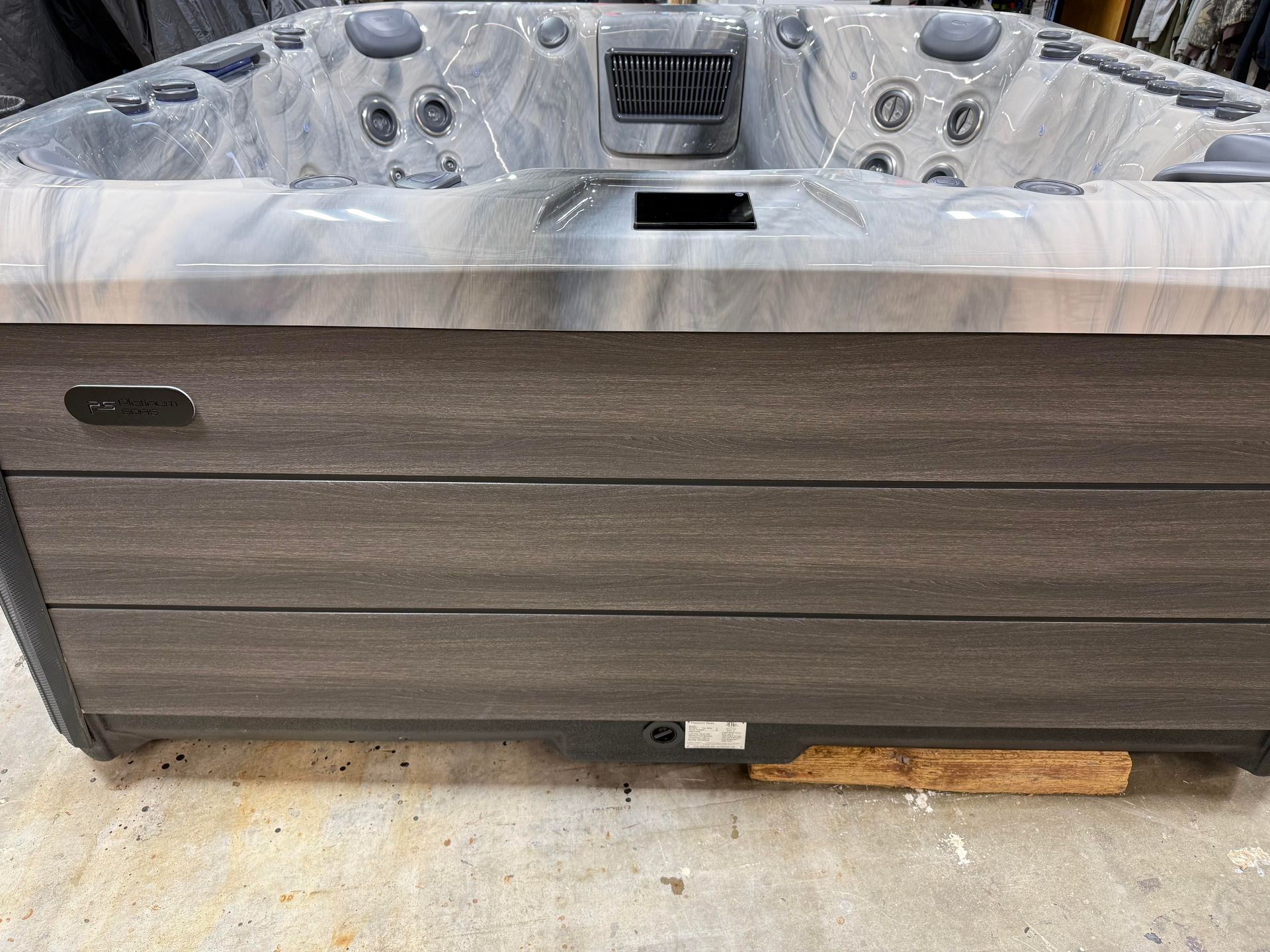Close-up of a gray and white hot tub with a dark gray wood-look paneling.
