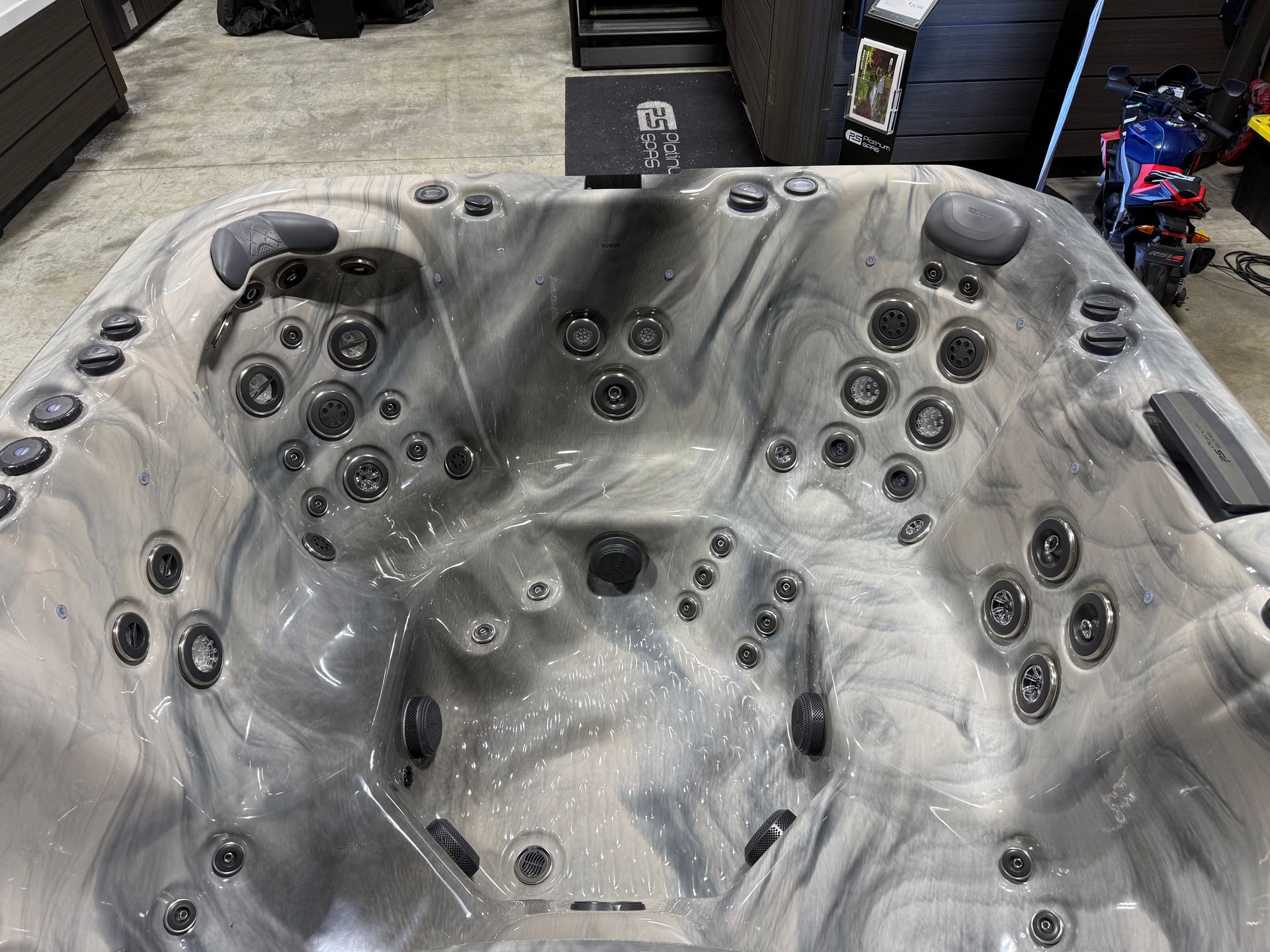 A close-up of a hot tub interior with gray and black marbled finish and multiple jets.