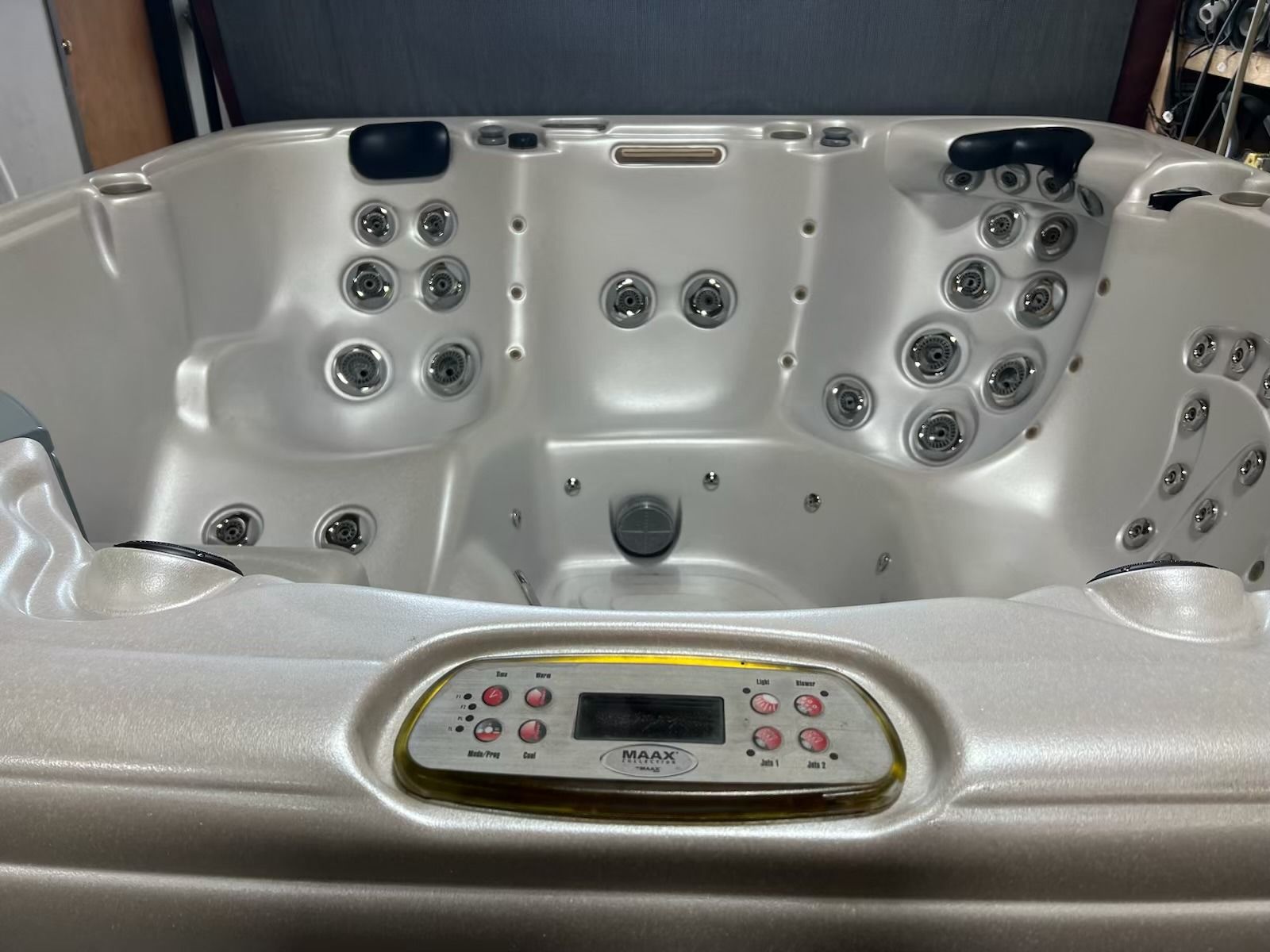 Hot tub with multiple jets, control panel, and open lid. White and silver tones.