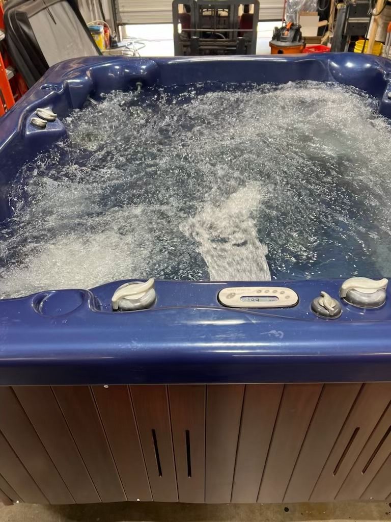 Bubbling blue hot tub, with wood-paneled sides, in a workshop setting.