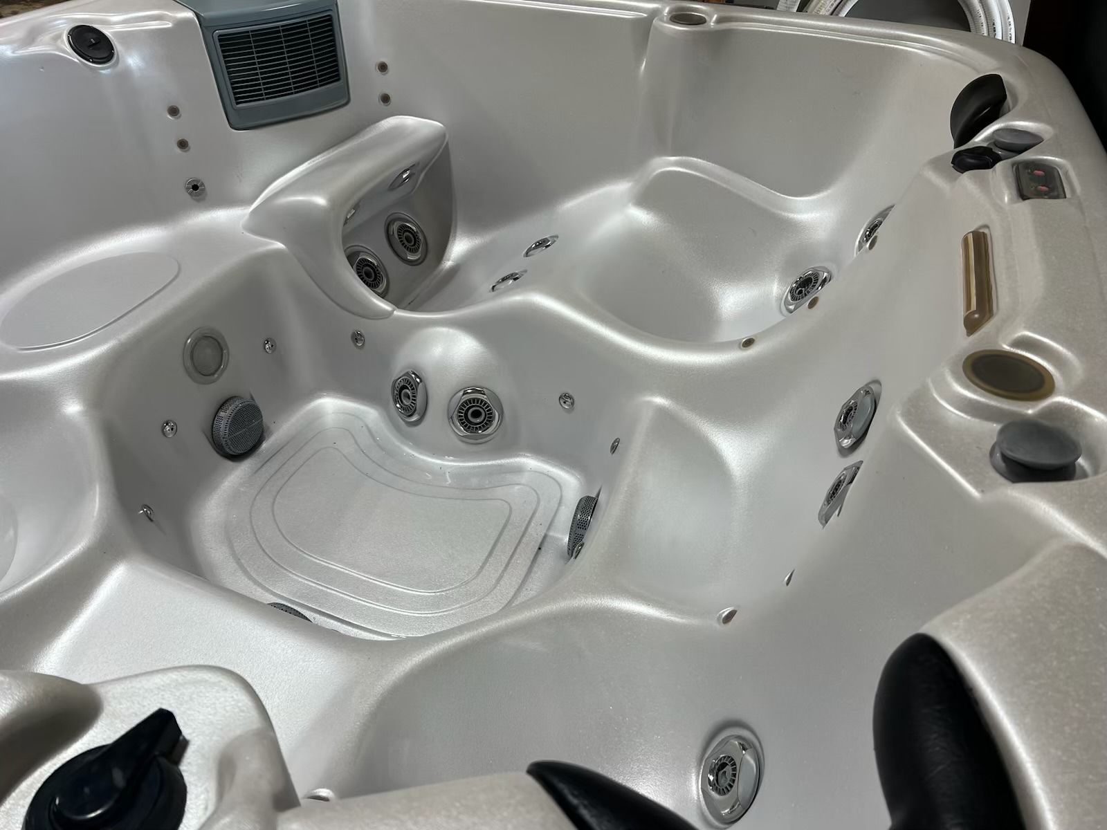 White hot tub interior with multiple molded seats, jets, and controls.