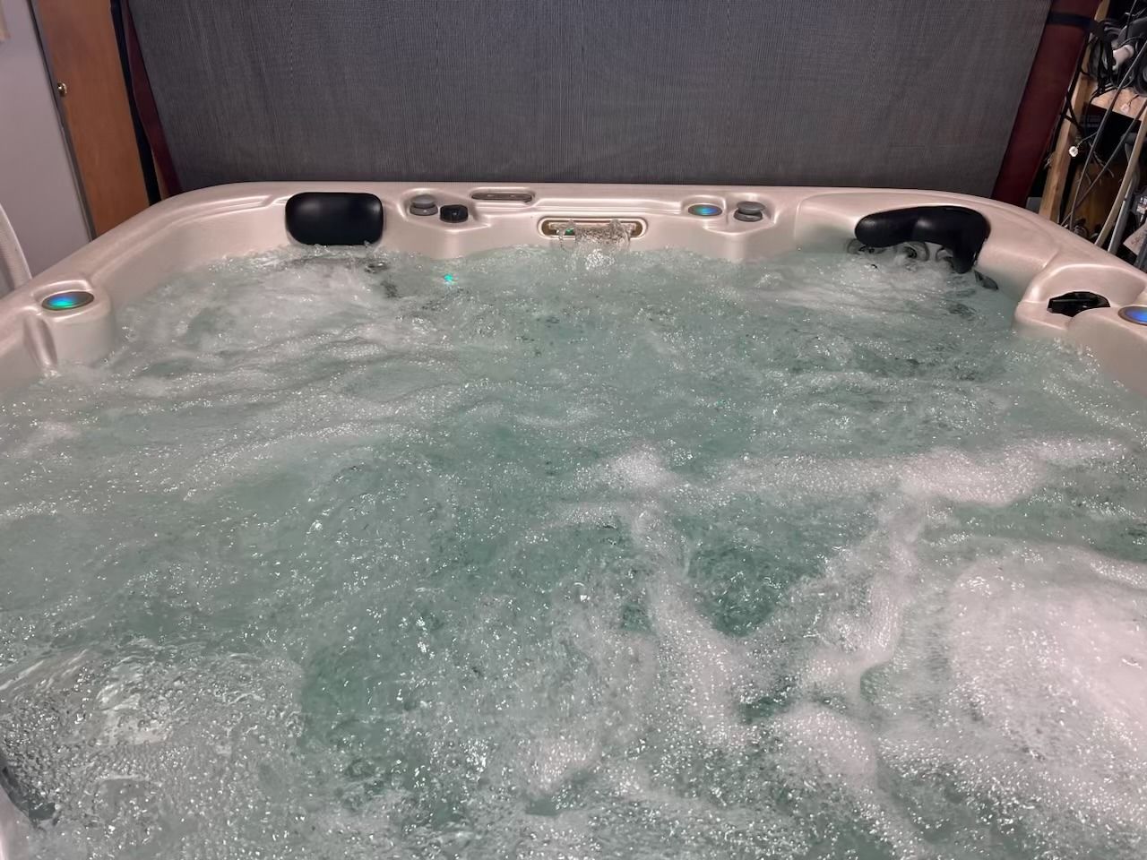 Bubbling hot tub with white interior, filled with turquoise water.