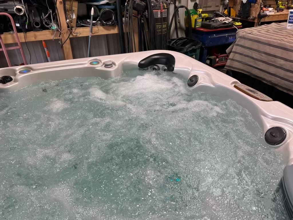 A hot tub with bubbly water, in a garage setting with tools and equipment visible in the background.