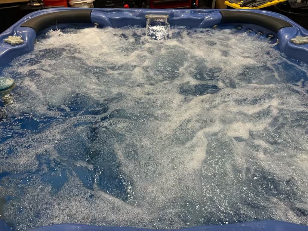 Blue hot tub filled with bubbling water; jets are on.