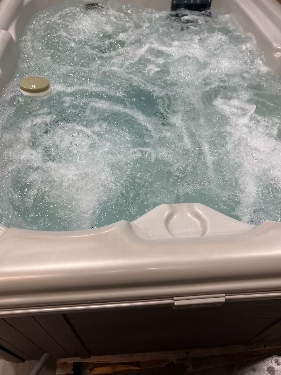 Bubbling hot tub with white interior, filled with turquoise water.