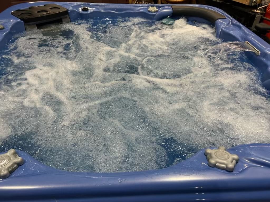 Blue hot tub filled with bubbling water; jets are activated.
