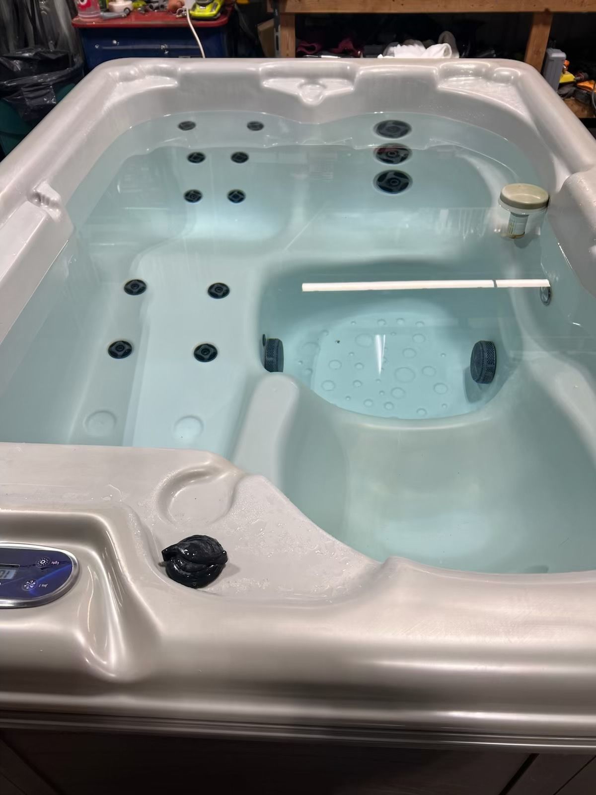 Hot tub filled with water, with jets and a floating chlorine dispenser.