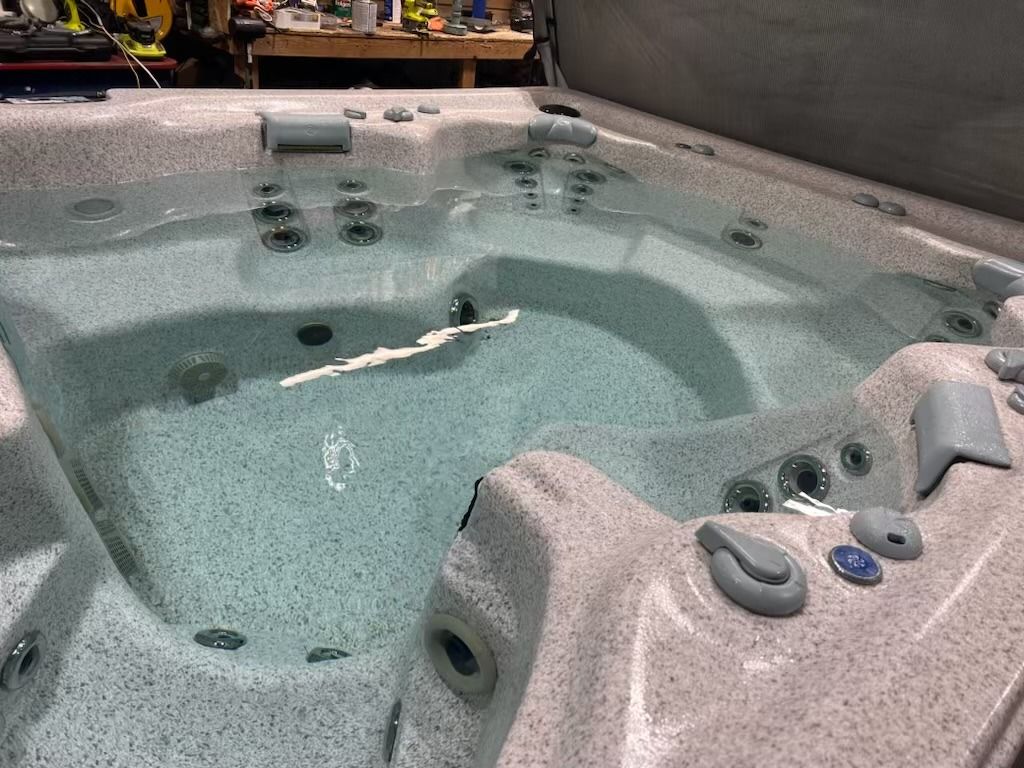 Hot tub with multiple jets, filled with clear water, and gray speckled surround.