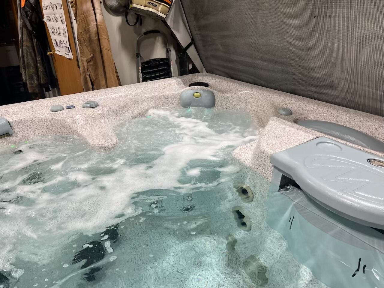 Hot tub with bubbling water, partially open lid, and control panel.