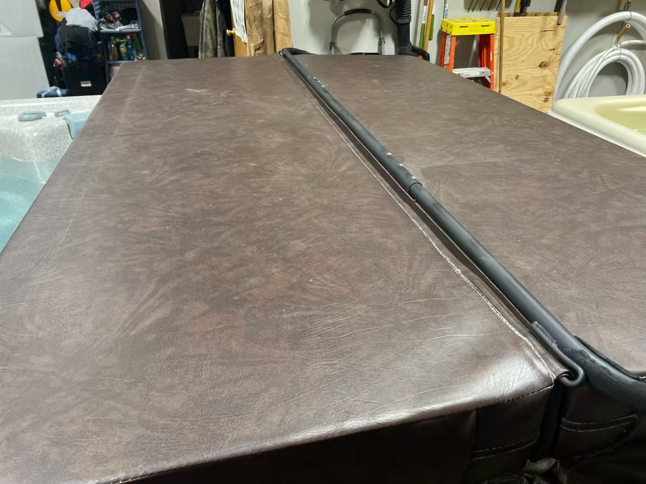 Brown hot tub cover, outdoors, folded in half.