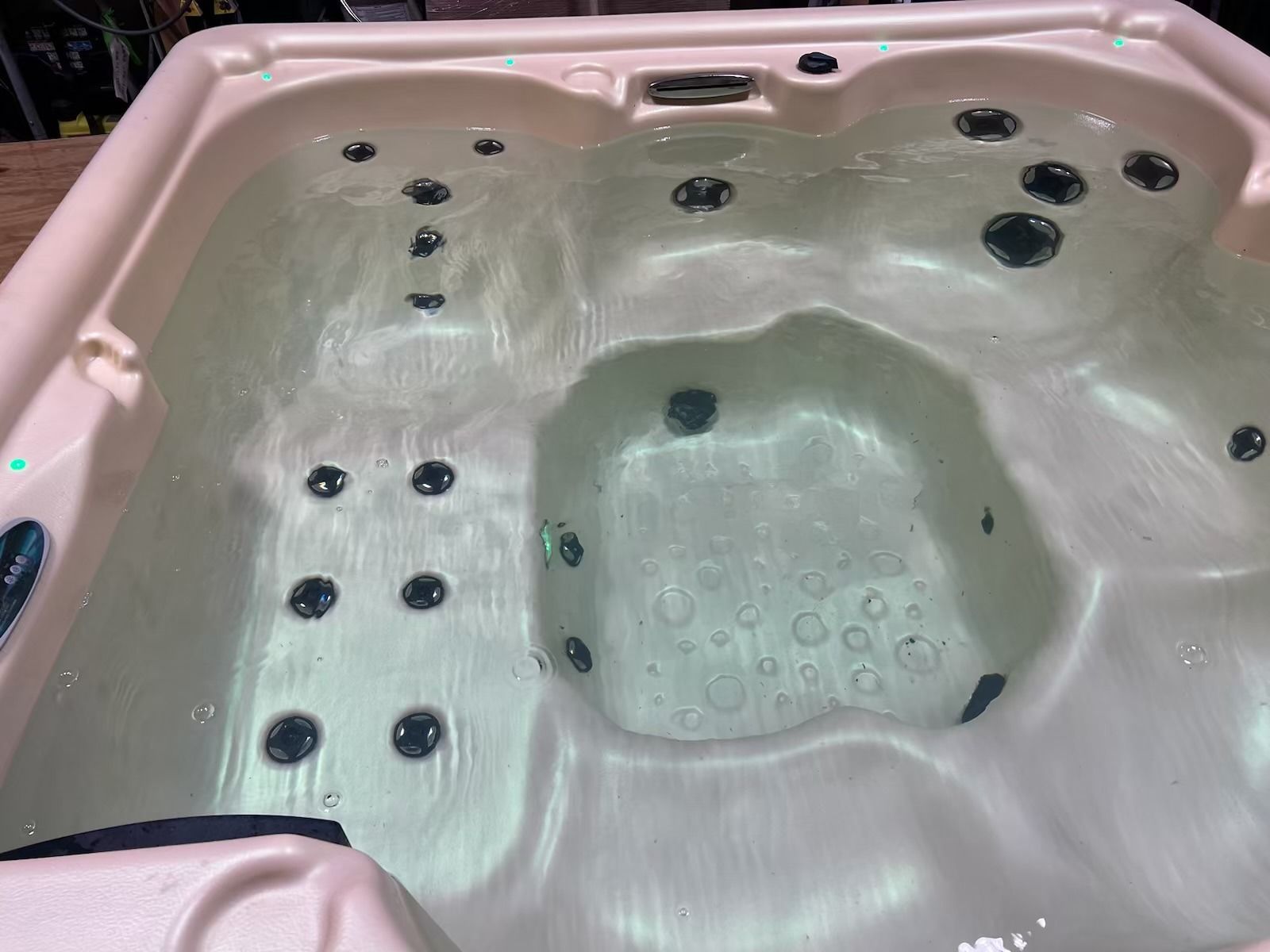 Hot tub filled with water, showing jets and molded seating in a light beige spa.