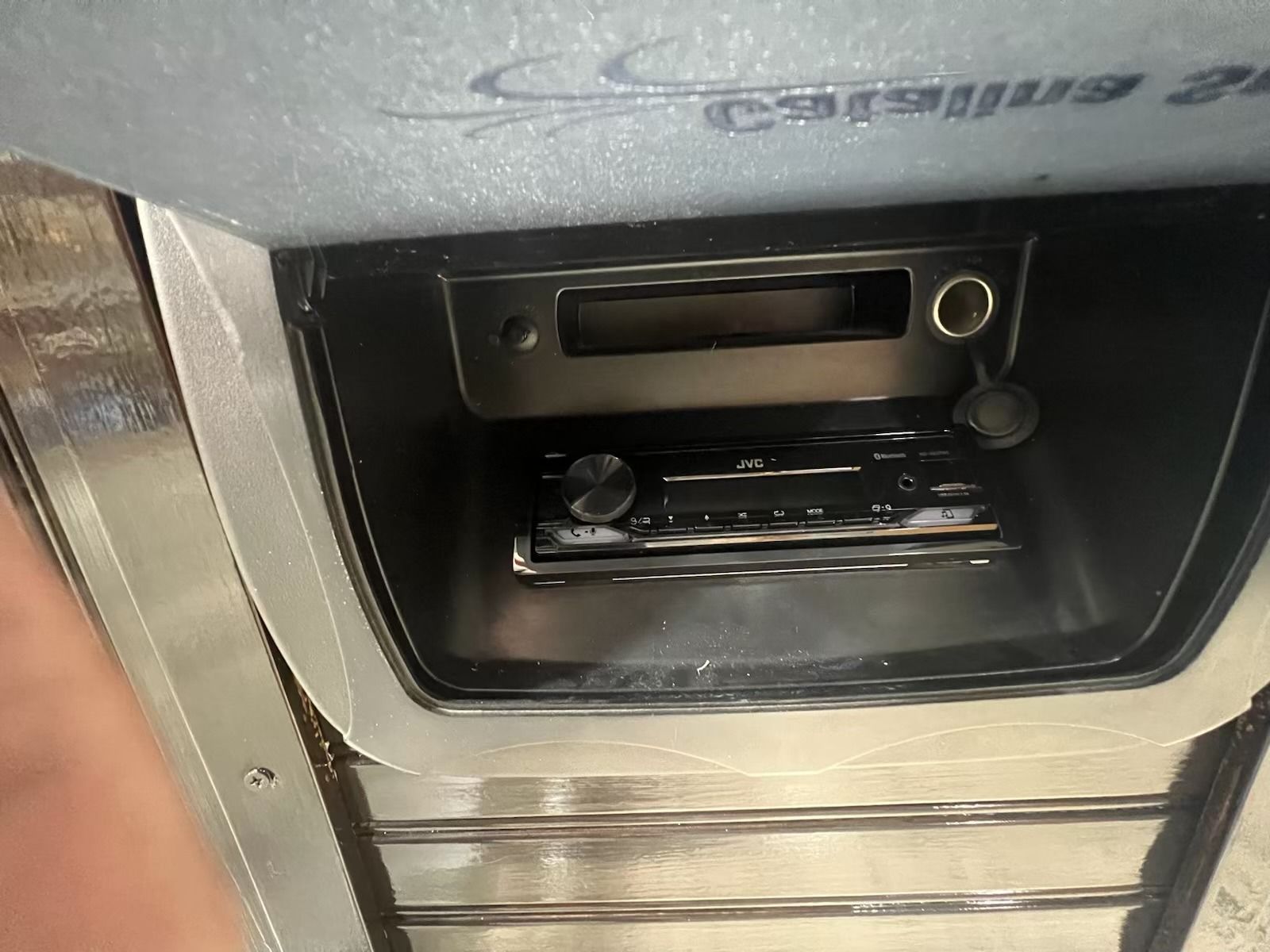 Dashboard with a car stereo and power outlet, mounted in a silver panel.
