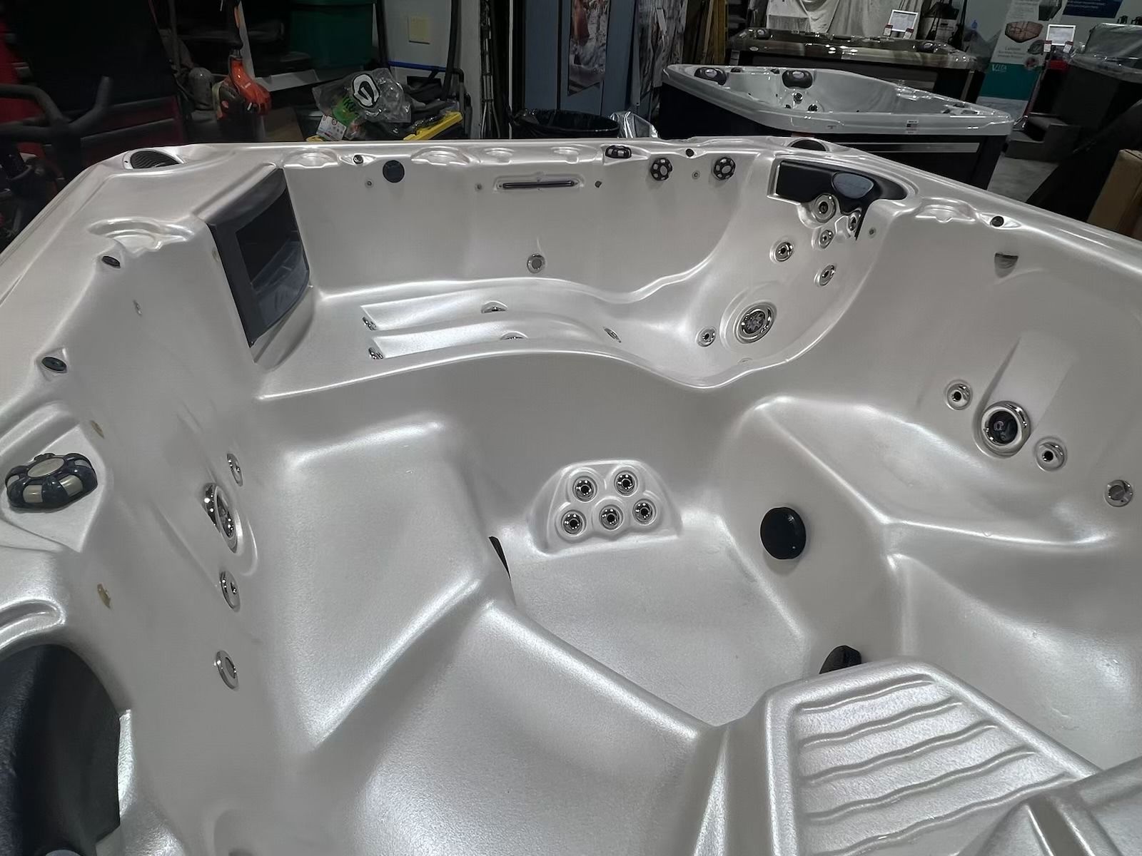 Empty, light gray hot tub interior with jets and seating areas.