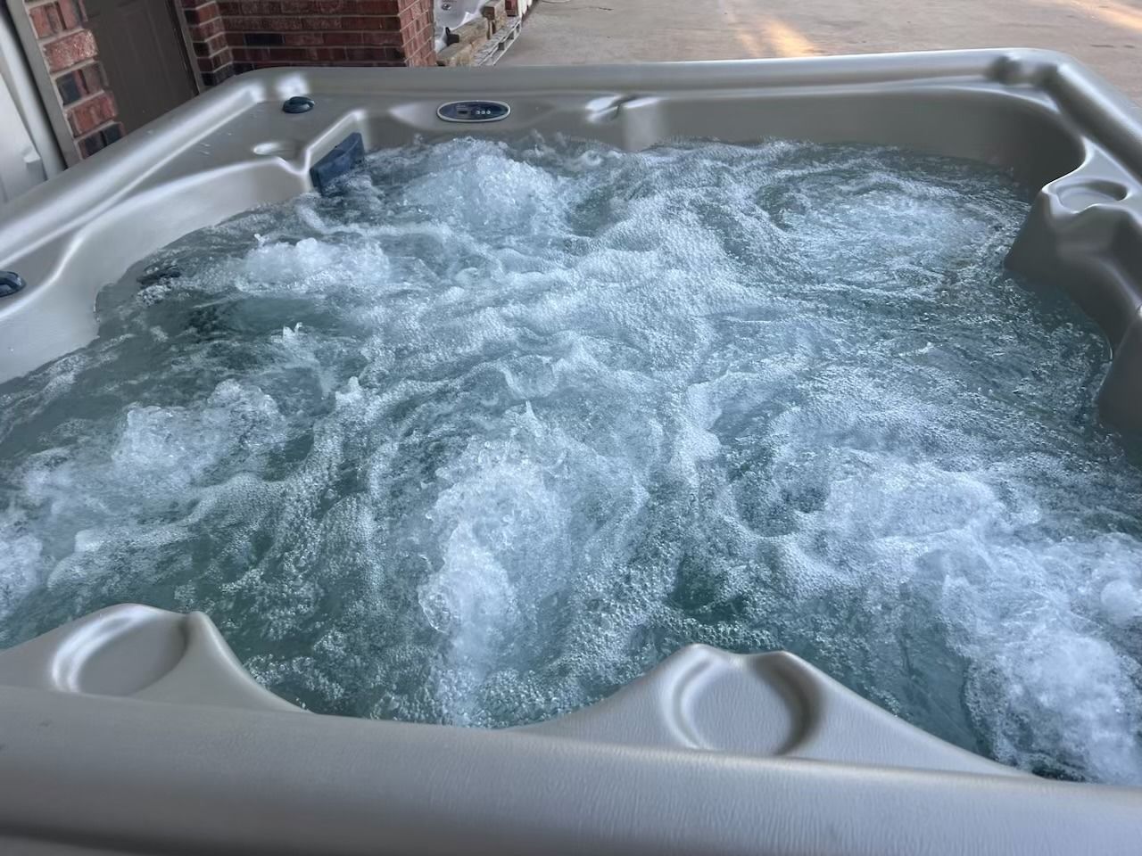 Bubbling hot tub with white water, set outdoors.