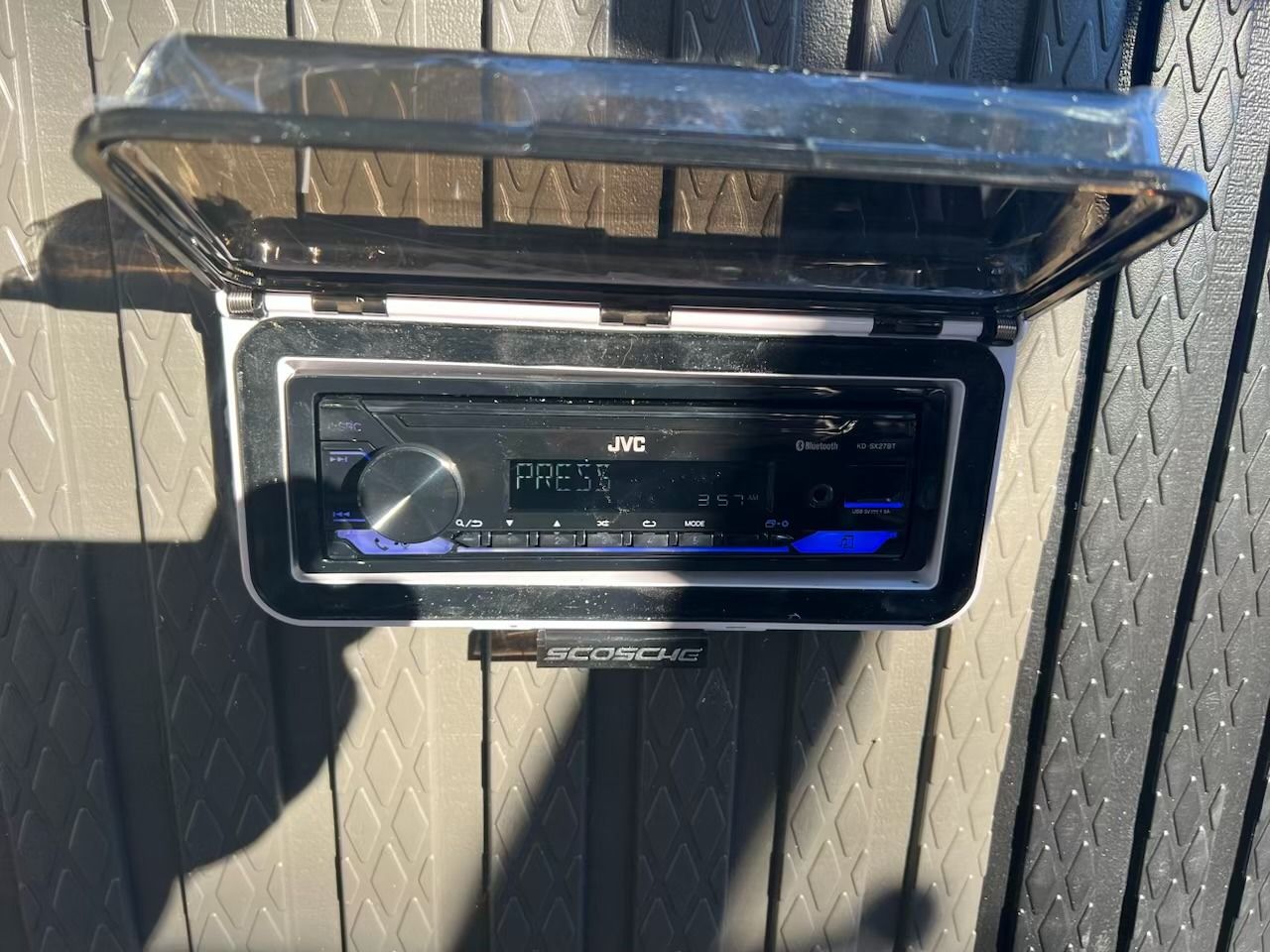 A JVC car stereo installed in a white weather-resistant housing with protective cover.