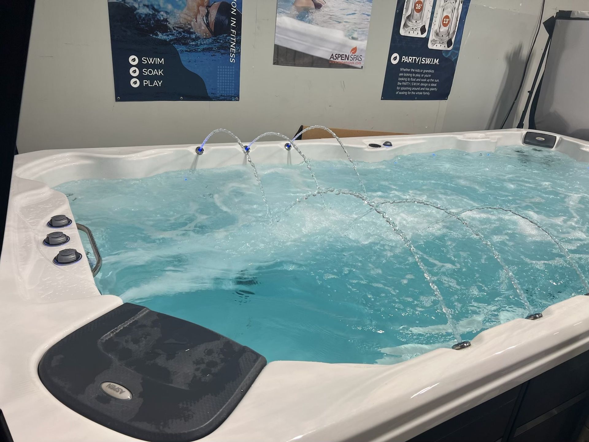 A rectangular swim spa with bubbling water and jets; control panel visible.