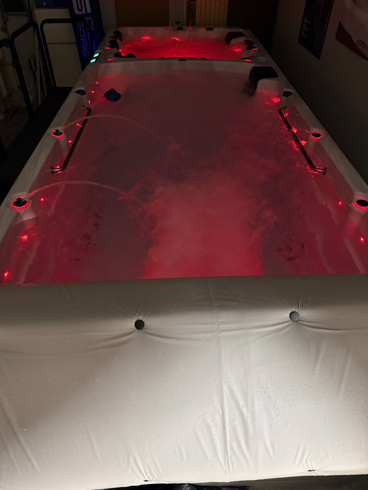 Large, rectangular hot tub illuminated with red lights, steam rising from the water.